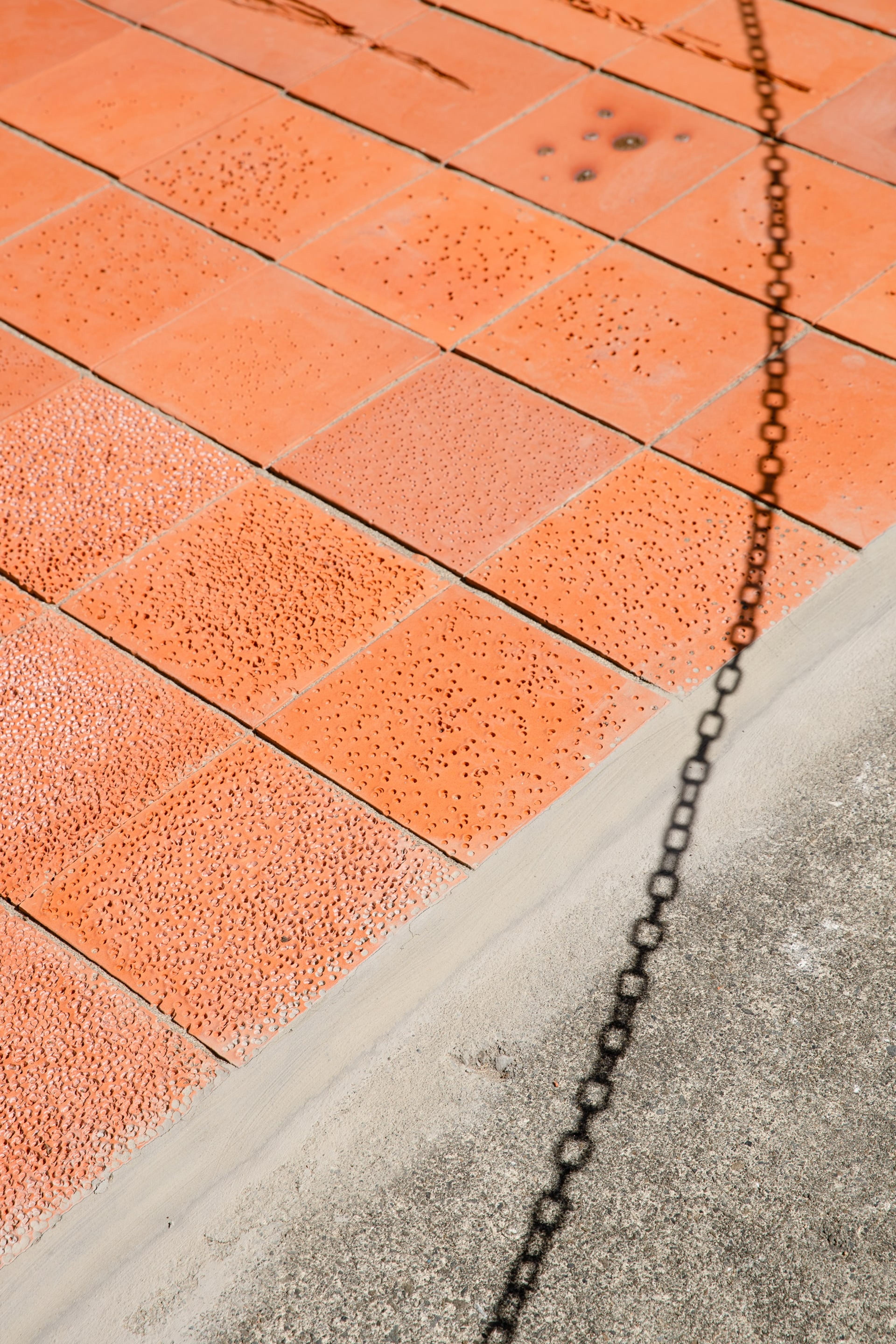 terracotta tiles with small dot marks and the shadow of a chain