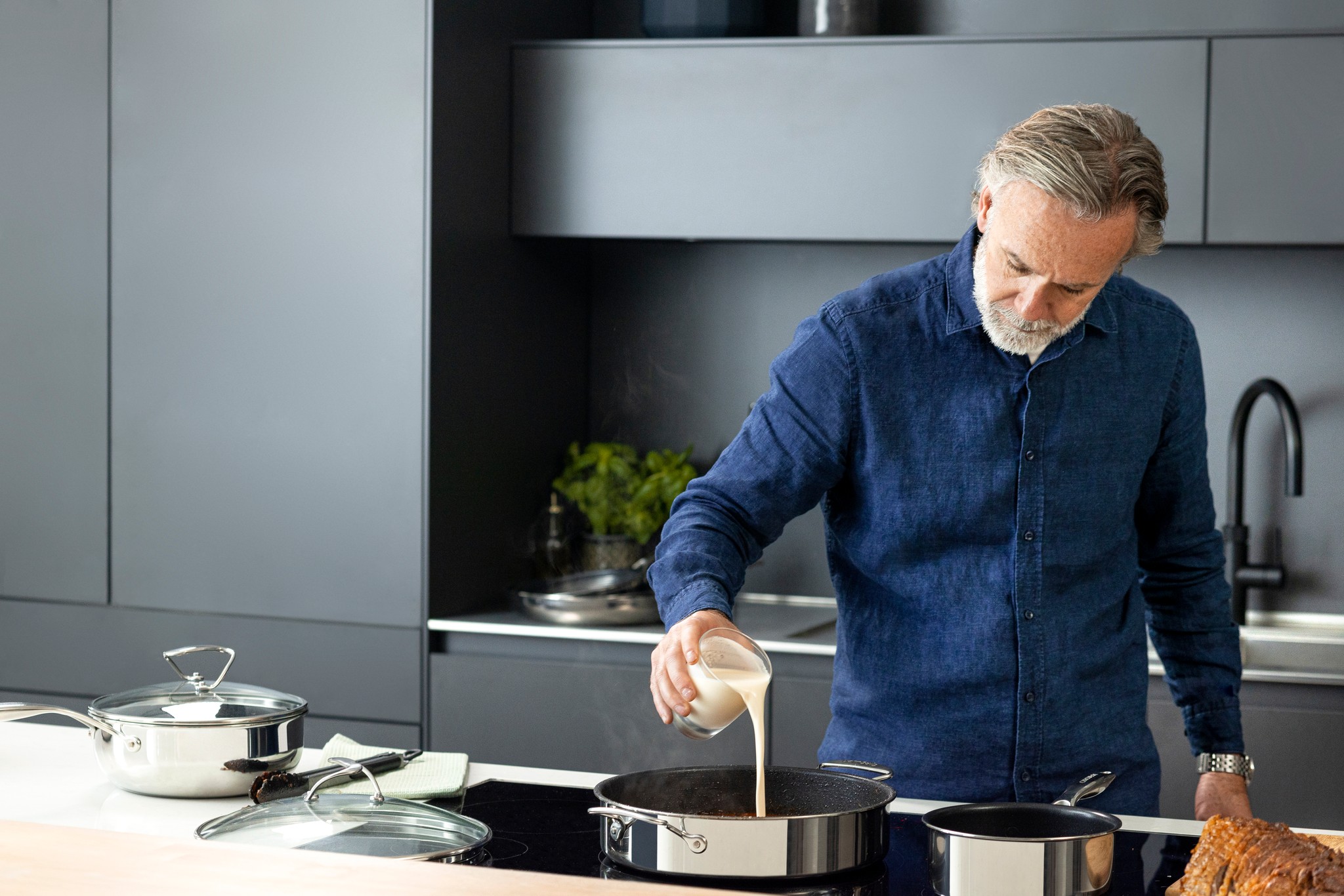 Marcus Wareing pouring cream into a Circulon pan in a domestic kitchen