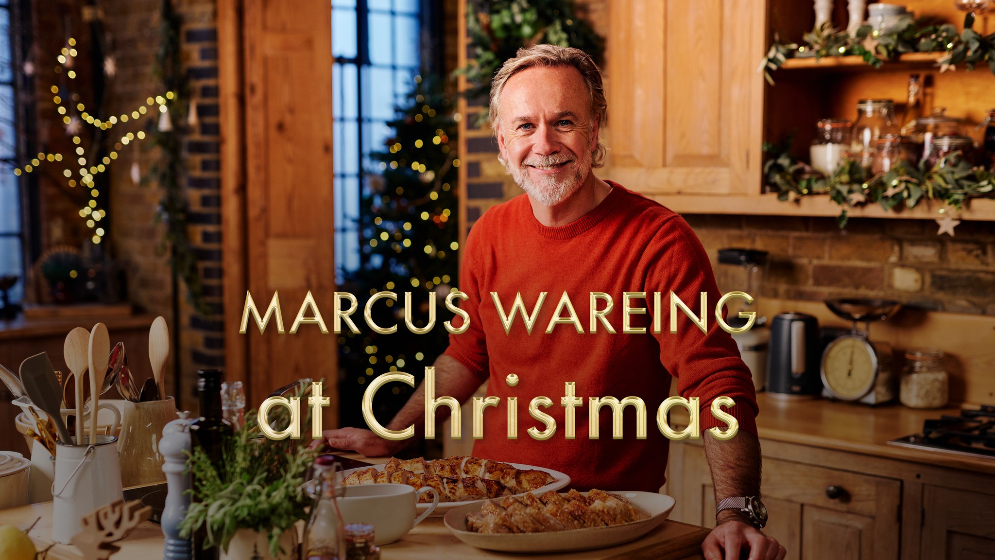 Marcus Wareing in a kitchen wearing a red jumper with words 'Marcus Wareing at Christmas' overlaid