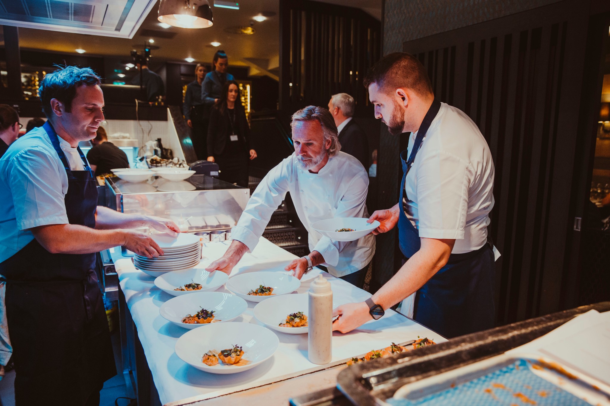 Mark Froydenlund, Jack Hazell and Marcus Wareing moving plates on the pass at Signature Food Festival