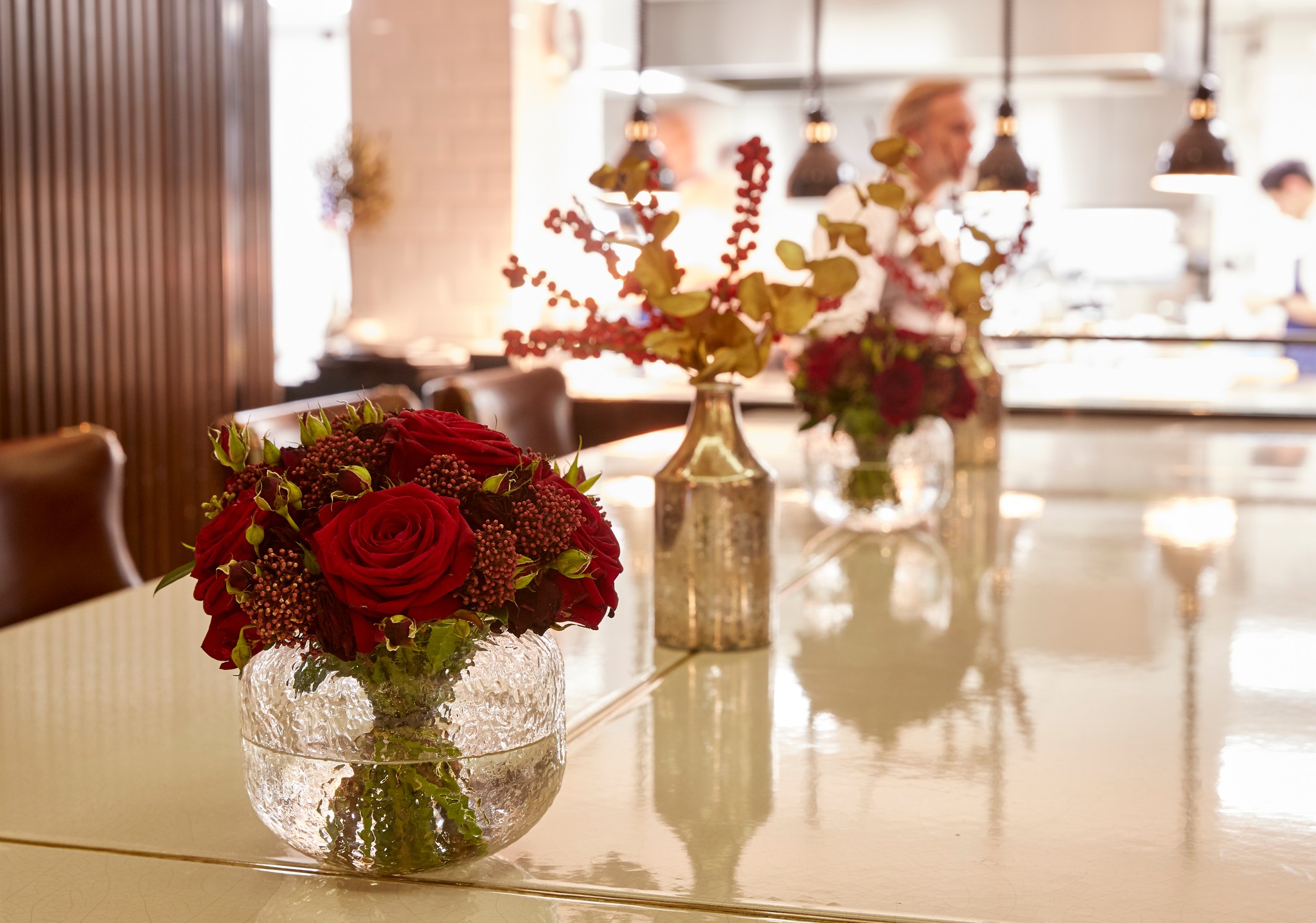 Three vases of red flowers placed in a vertical row on the Chef's Table at Marcus Belgravia 