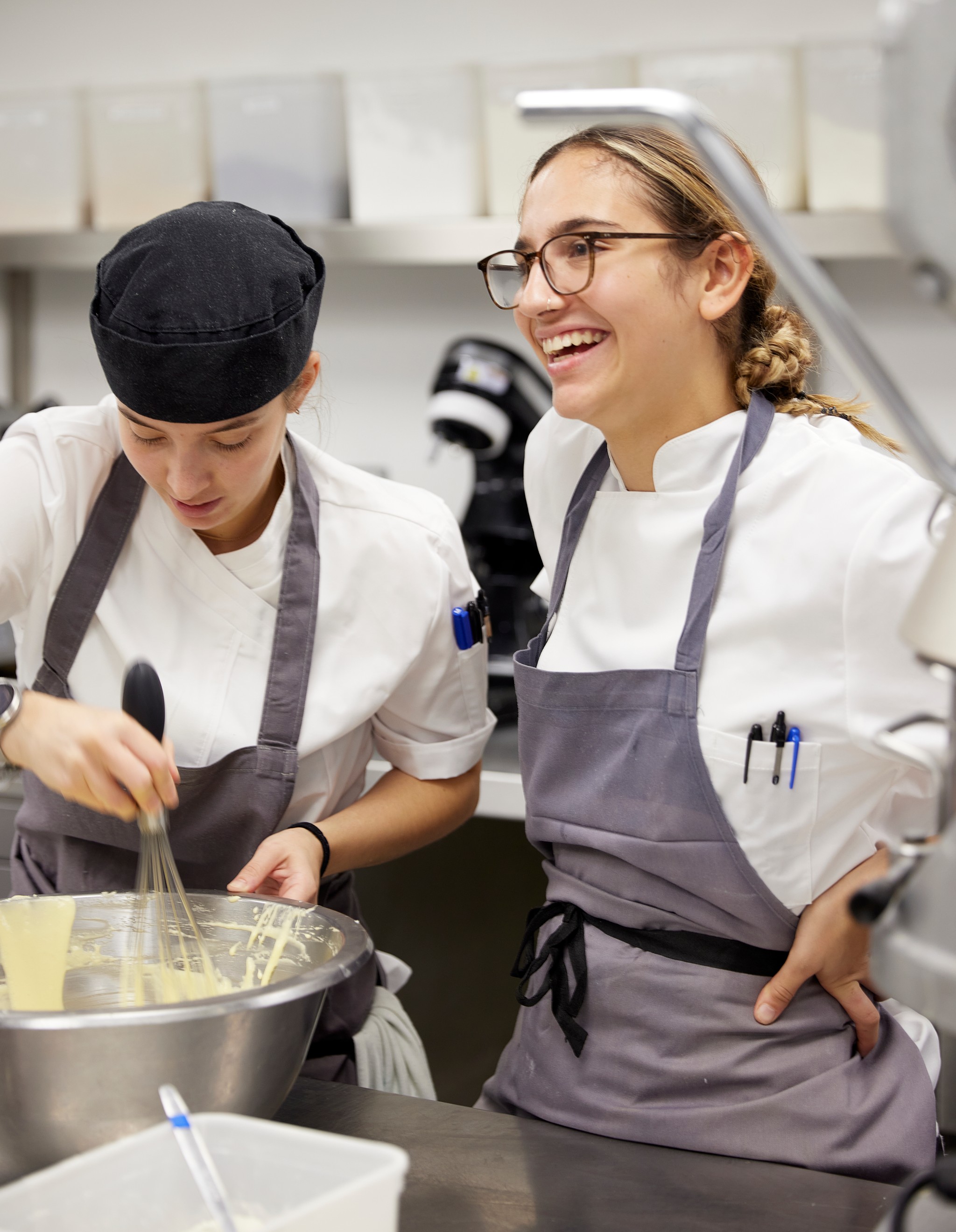 Two female chefs standing in front of a bowl