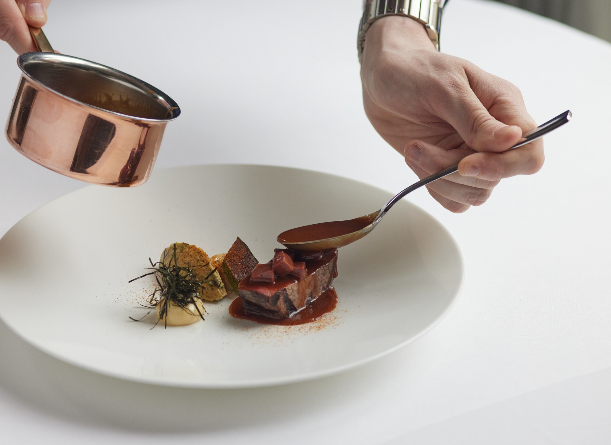 Hand spooning sauce onto Galloway beef fillet dish from Marcus Belgravia