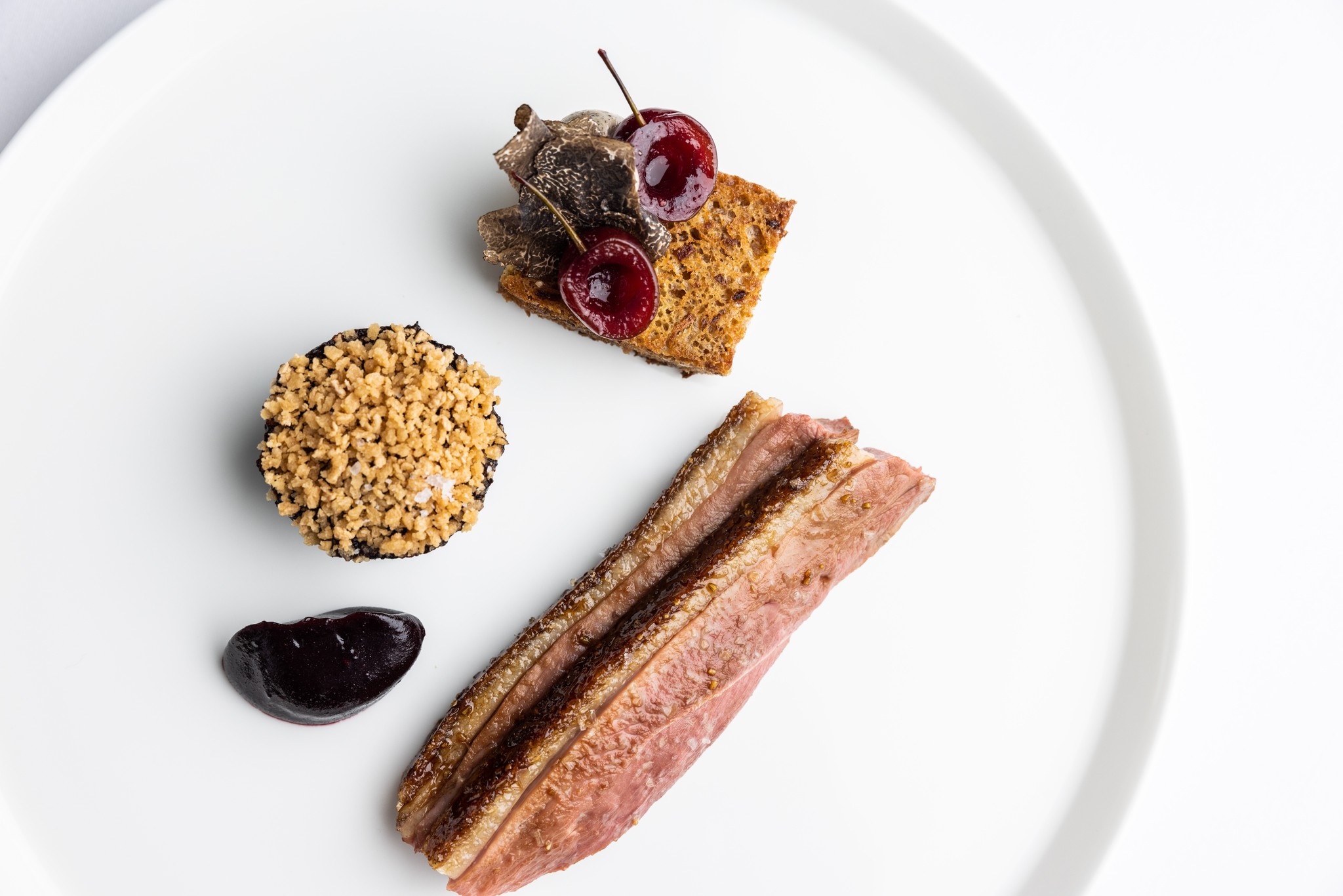 Overhead shot of Devonshire duck with cherries and beetroot on a large white plate
