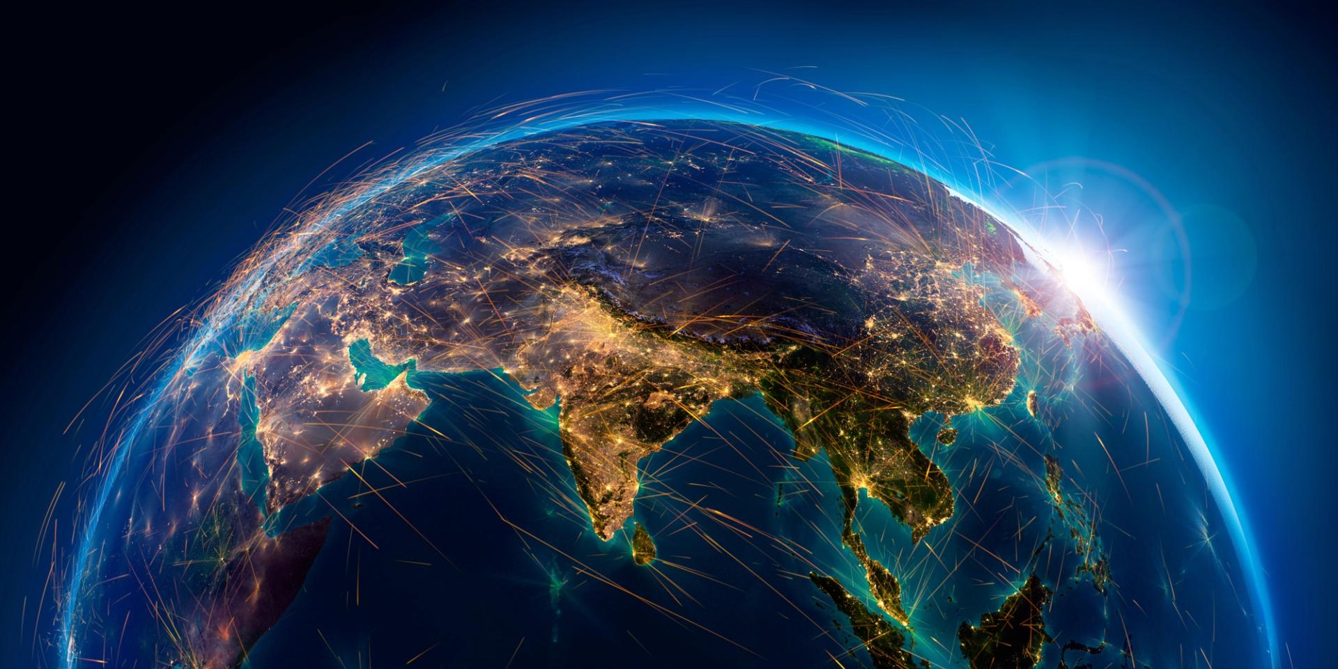 Earth at night viewed from space over India and Asia, with glowing lines representing global connectivity networks