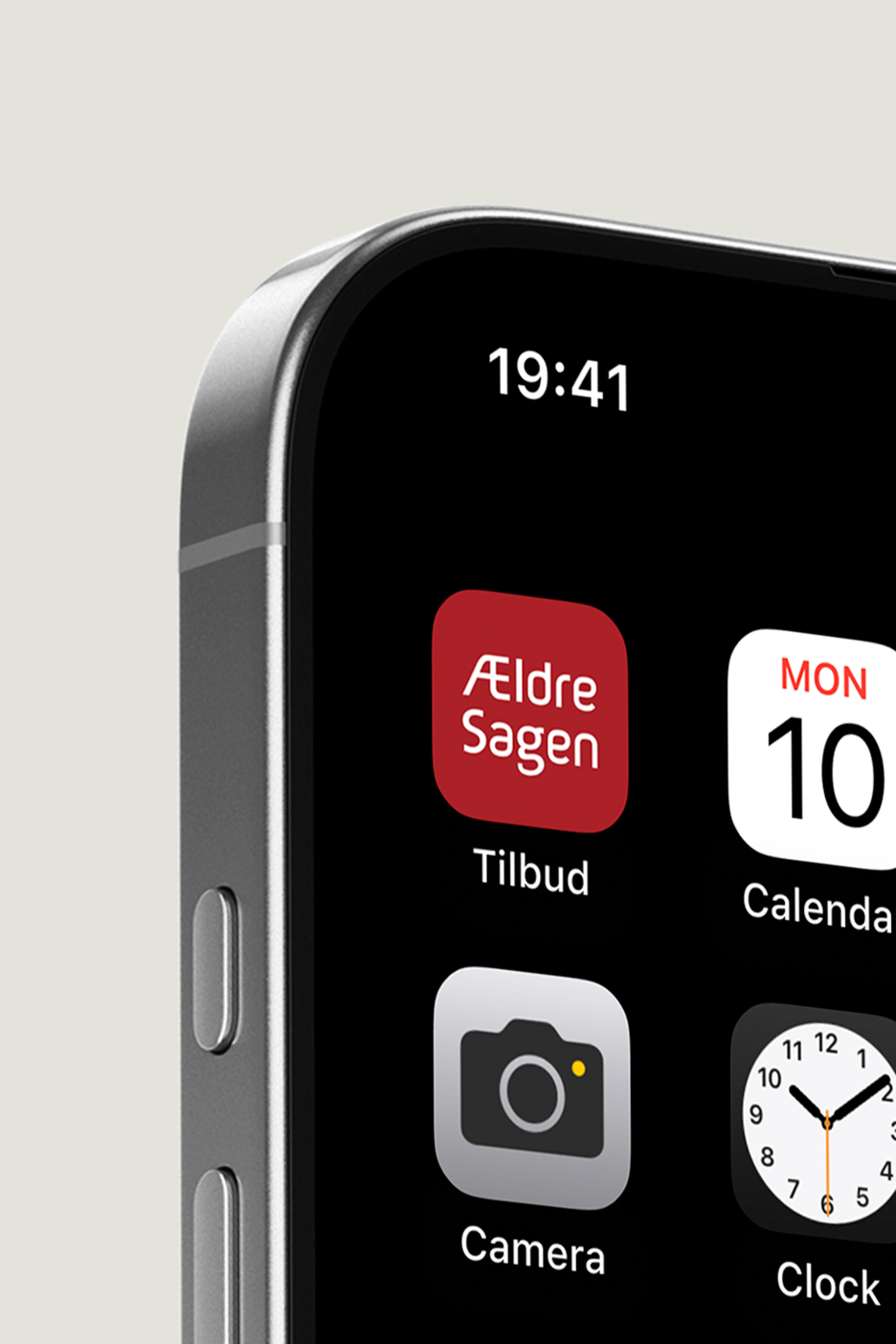 Close-up view of a smartphone screen showing the top corner, featuring the time '19:41' and various app icons including 'Ældre Sagen Tilbud' with a red background, 'Calendar,' 'Camera,' and 'Clock,' displayed on a sleek metal frame with a minimalist design. Perfect for illustrating modern mobile interface design and app arrangement.