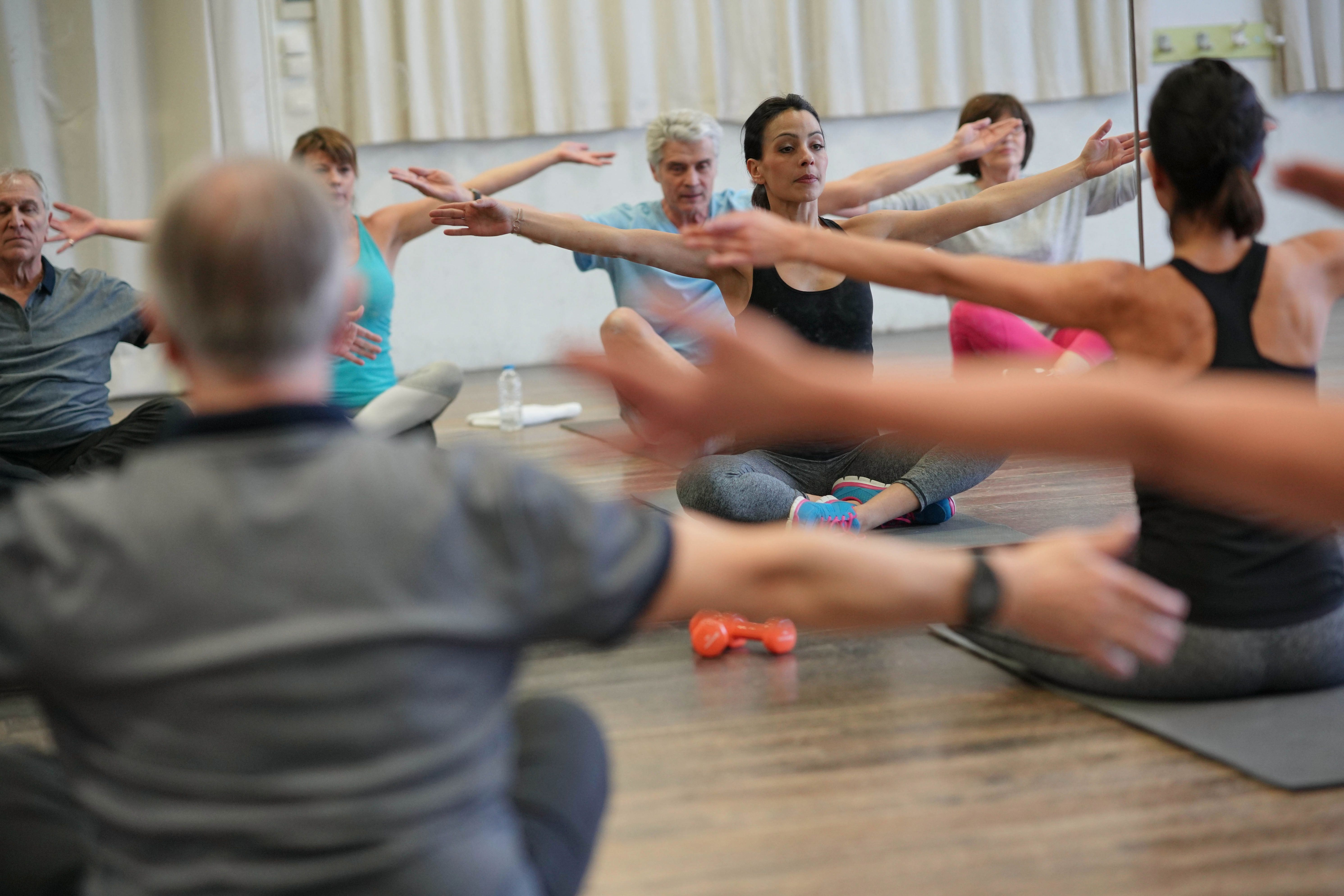 Older adults stretching with arms outstretched in a supervised group exercise class