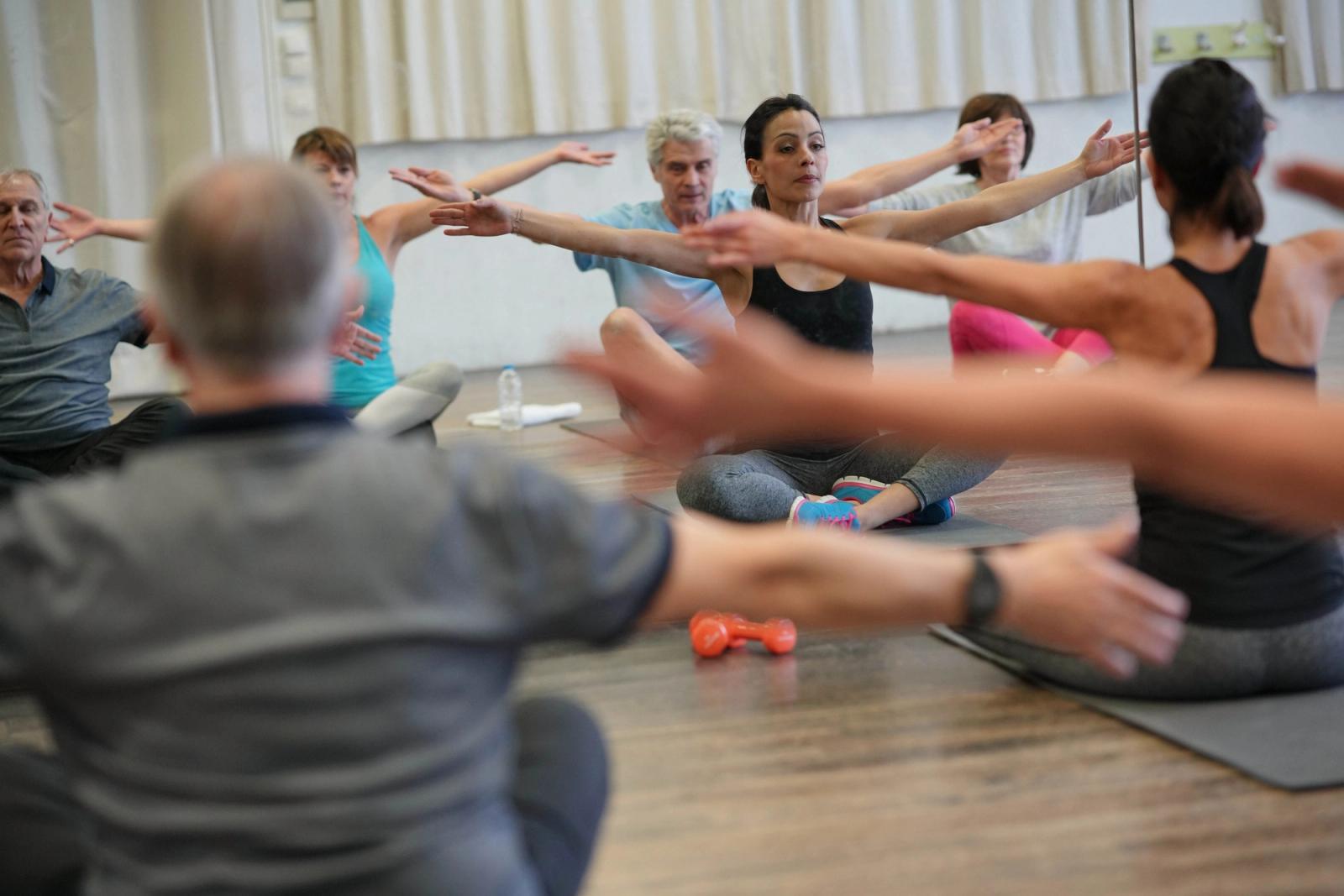 Older adults stretching with arms outstretched in a supervised group exercise class