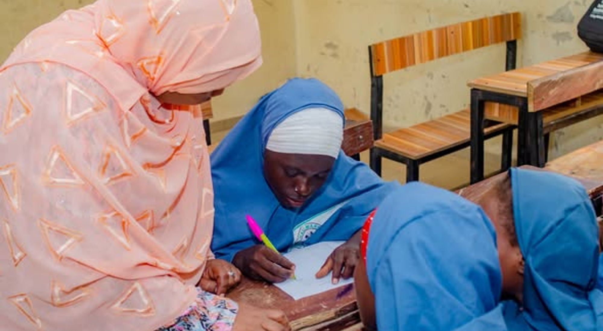 A facilitator supports schoolgirls during a learning activity.