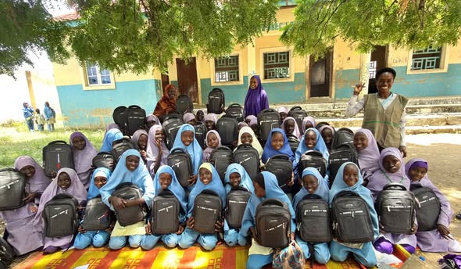 Schoolgirls hold backpacks during a HALI-supported education activity.