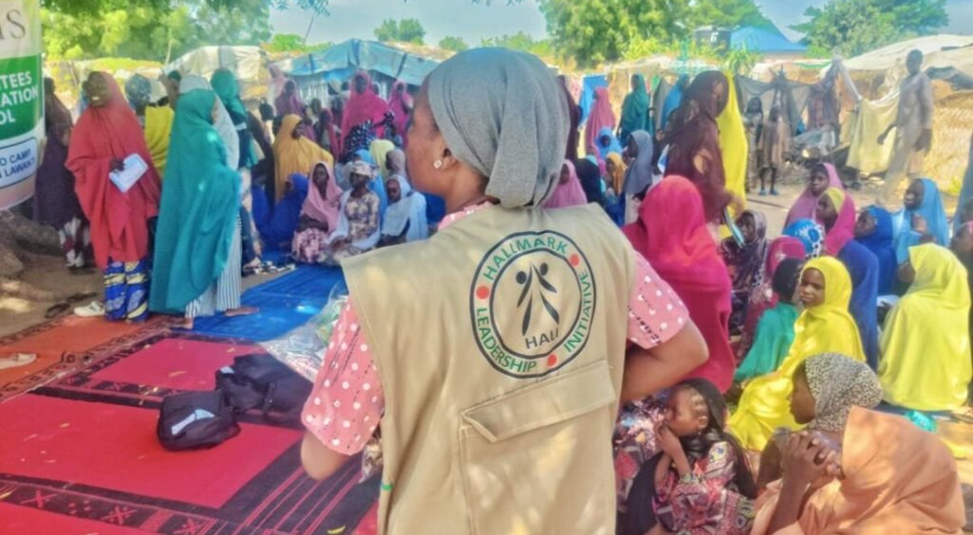 A HALI team member works alongside women and children during a community activity.