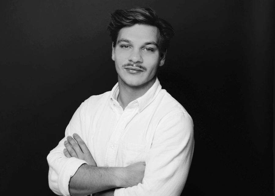 Porträt von Cedric Zuber mit verschränkten Armen vor dunklem Hintergrund