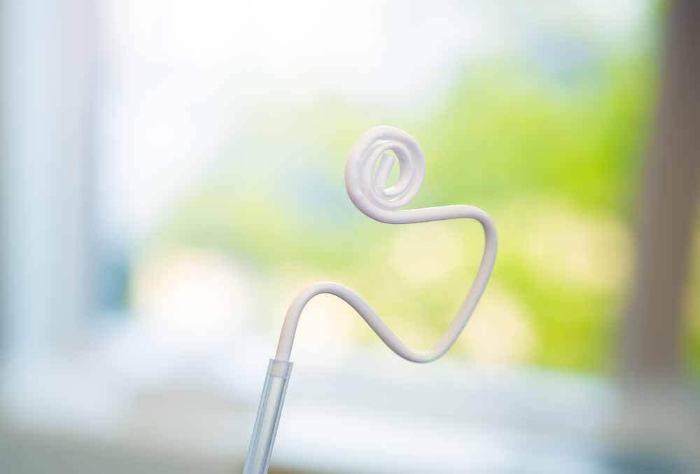Hvit spiralformet tanntrådholder mot uskarp grønn bakgrunn.