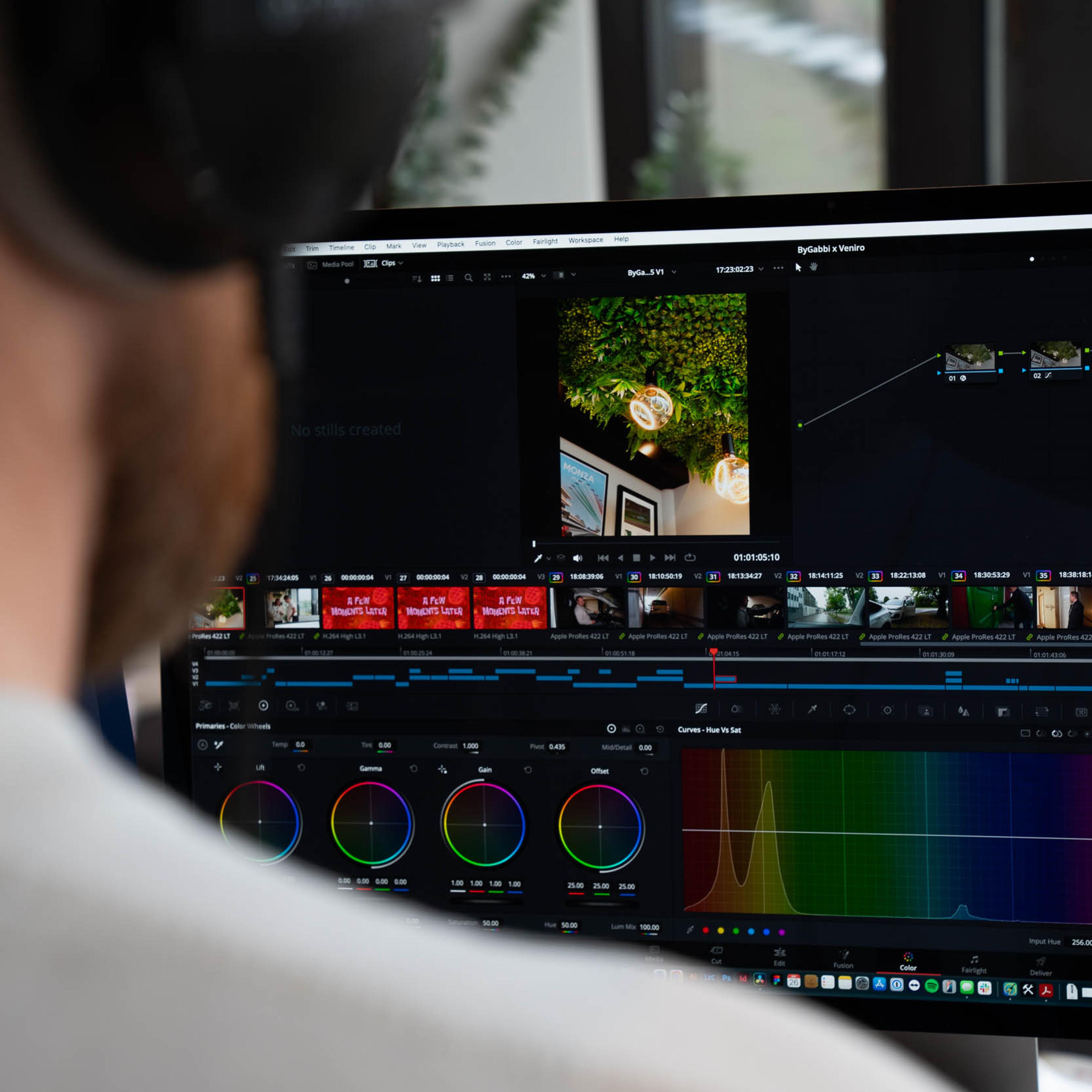 Videograf arbeider ved datamaskinen med fargegradering og redigering av videoinnhold i profesjonell redigeringsprogramvare.