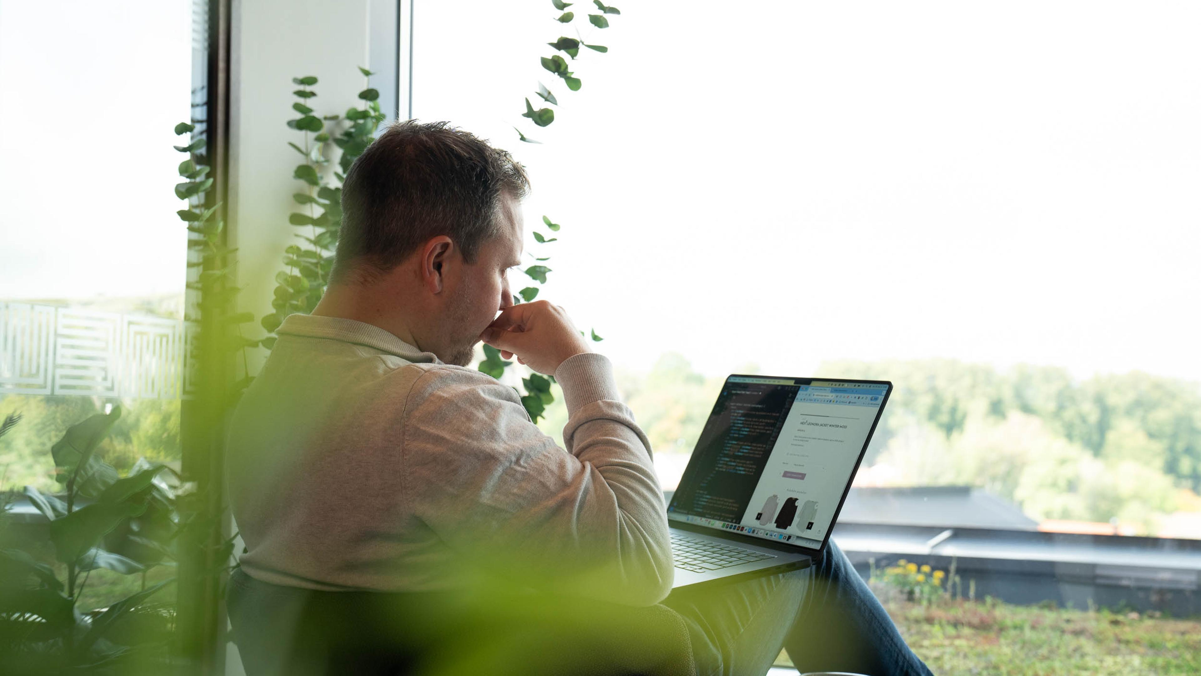 Utvikler setter opp integrasjon mellom kassesystem og nettbutikk på laptop, med kode og produktside på skjermen