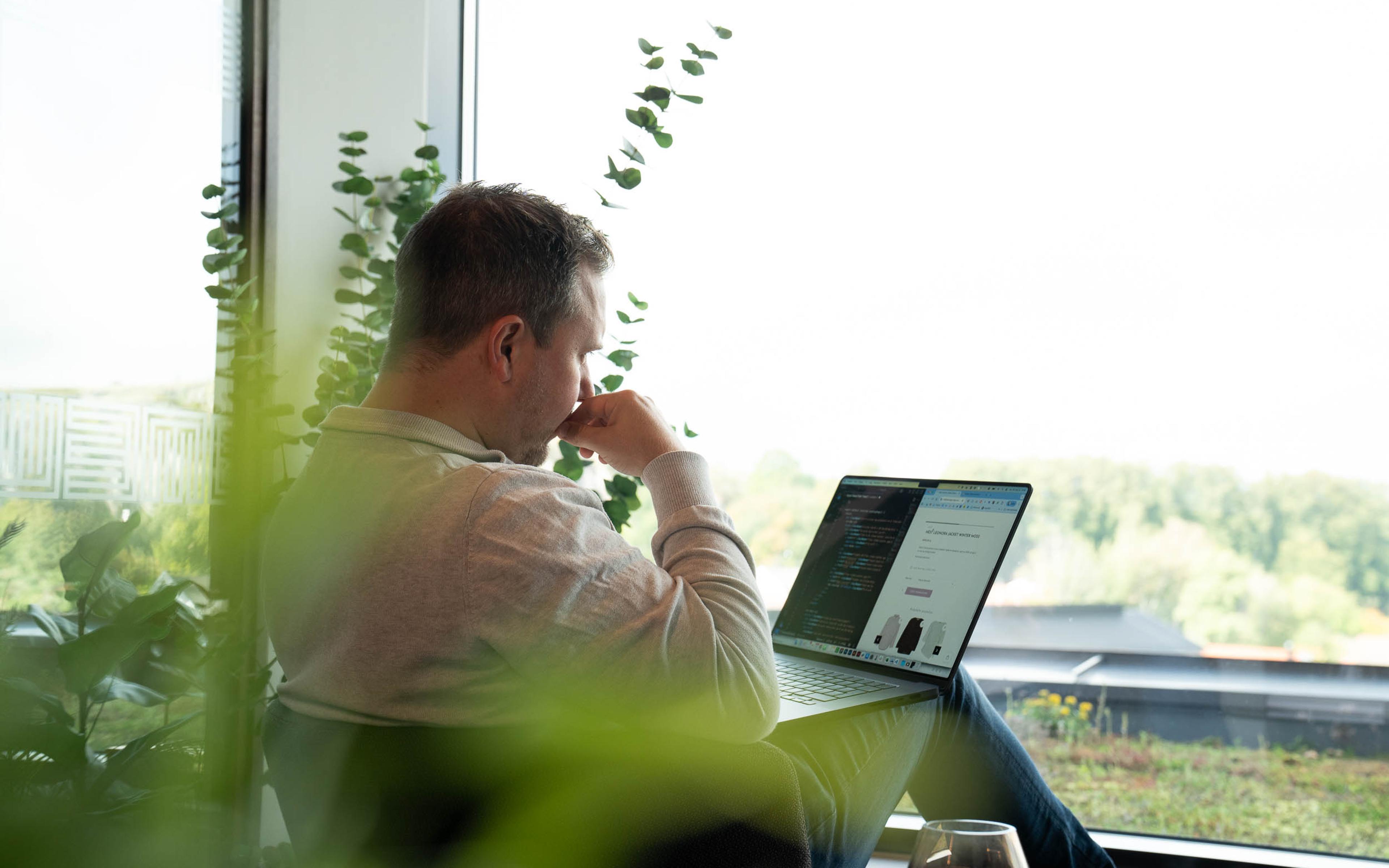 Utvikler setter opp integrasjon mellom kassesystem og nettbutikk på laptop, med kode og produktside på skjermen