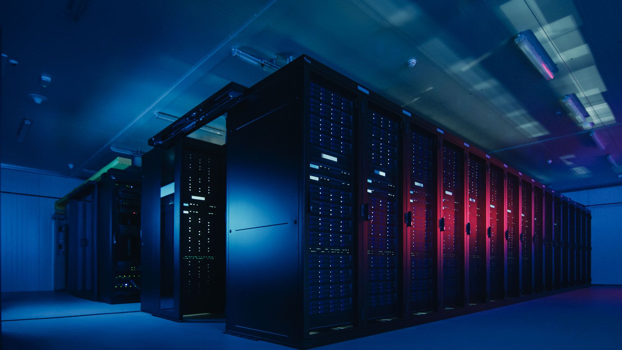 Serverrack med blå og røde LED-lys i moderne datakammer, illustrerer skyinfrastruktur og digital teknologi.