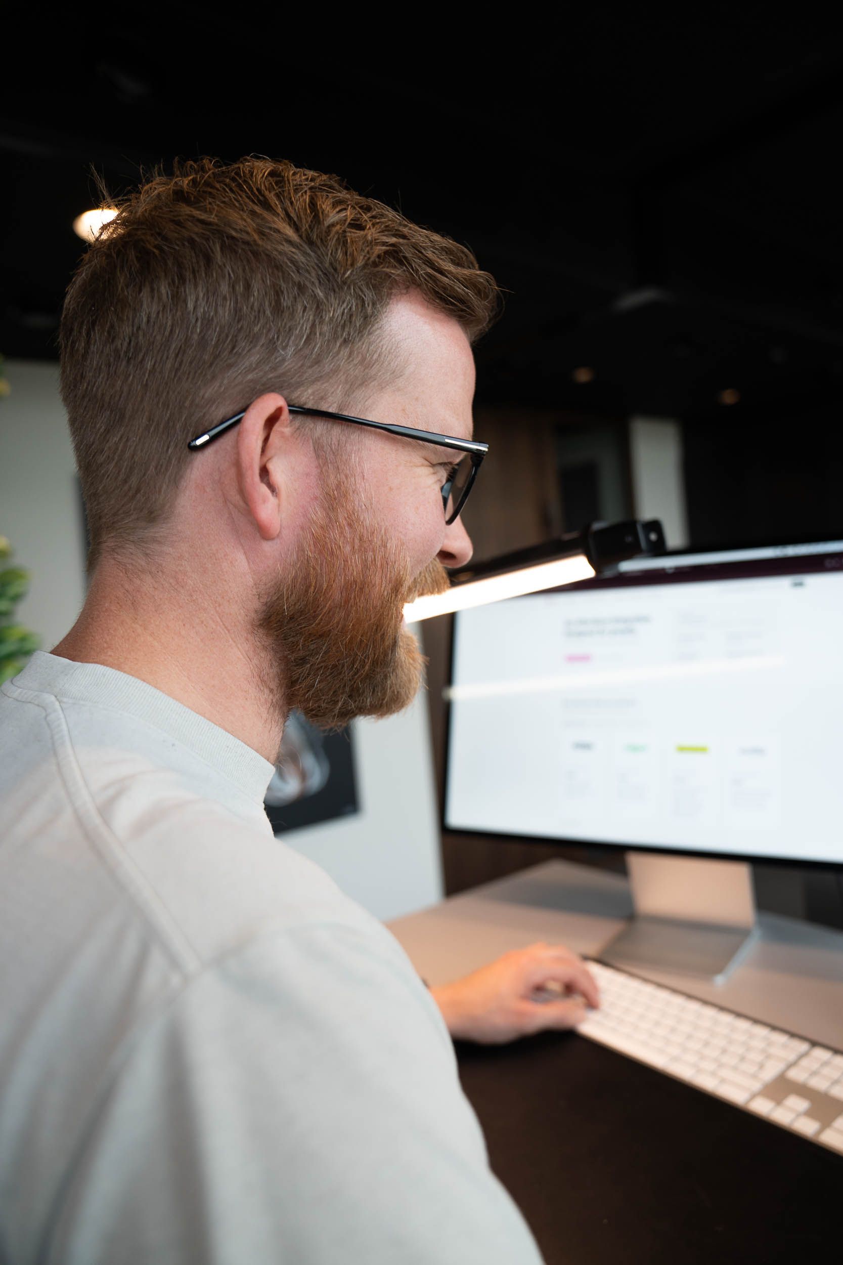 Utvikler med briller jobber med en nettside på en iMac på kontoret