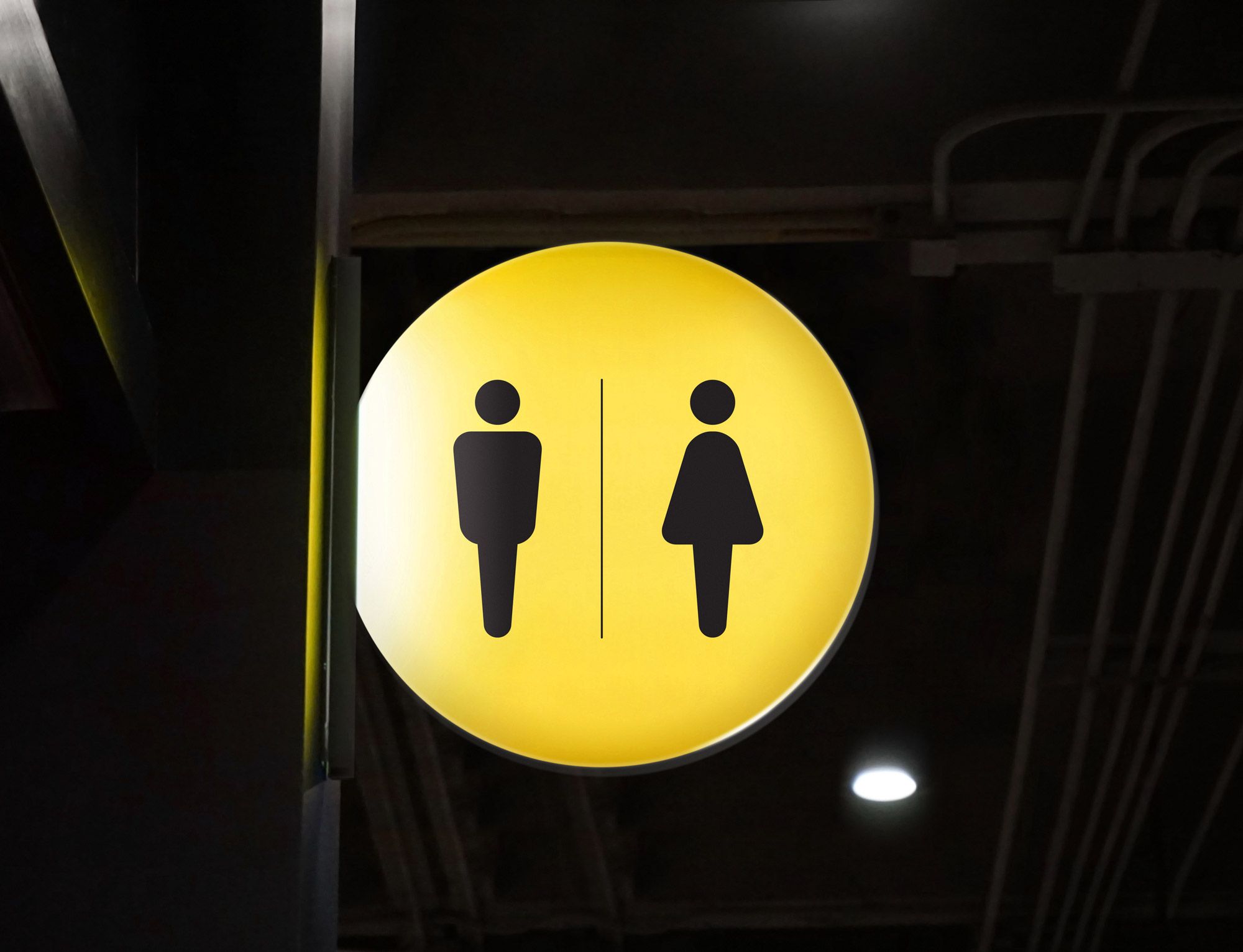 Gult sirkulært skilt med piktogrammer for mannlig og kvinnelig toalett, adskilt av vertikal strek.