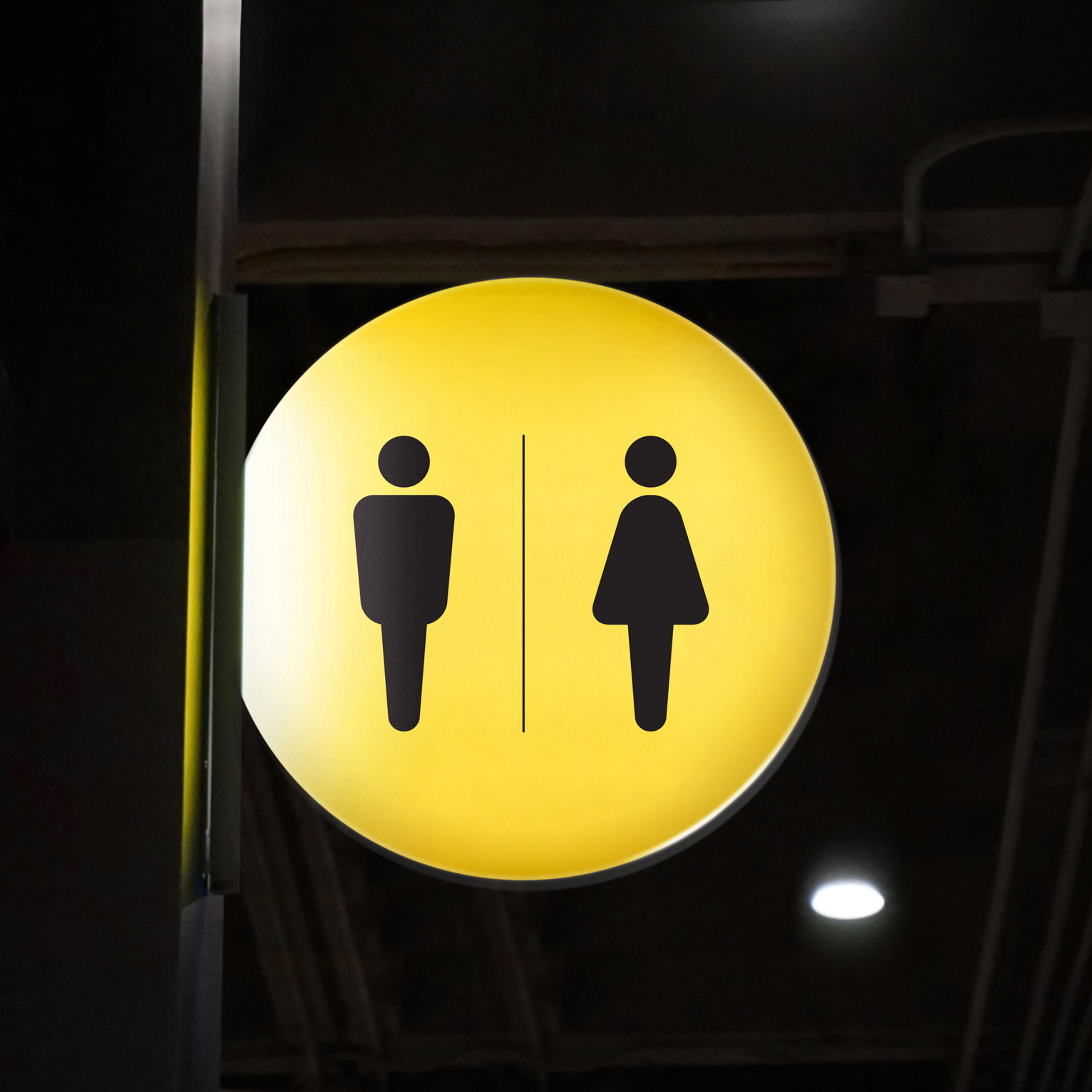 Gult sirkulært skilt med piktogrammer for mannlig og kvinnelig toalett, adskilt av vertikal strek.