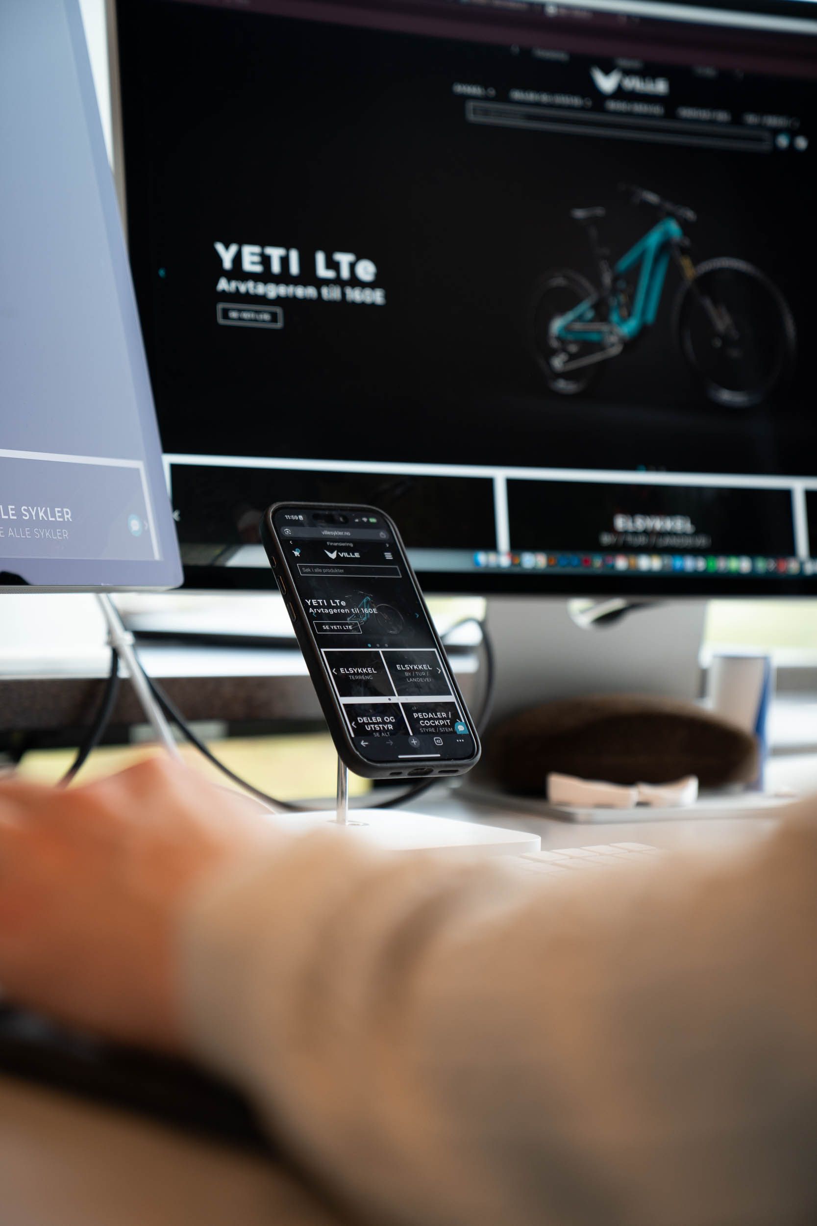 Mobiltelefon og desktop-skjerm viser Yeti LTc-sykkel fra Vitus-merket med svart grensesnitt og turkis sykkeldetaljer.
