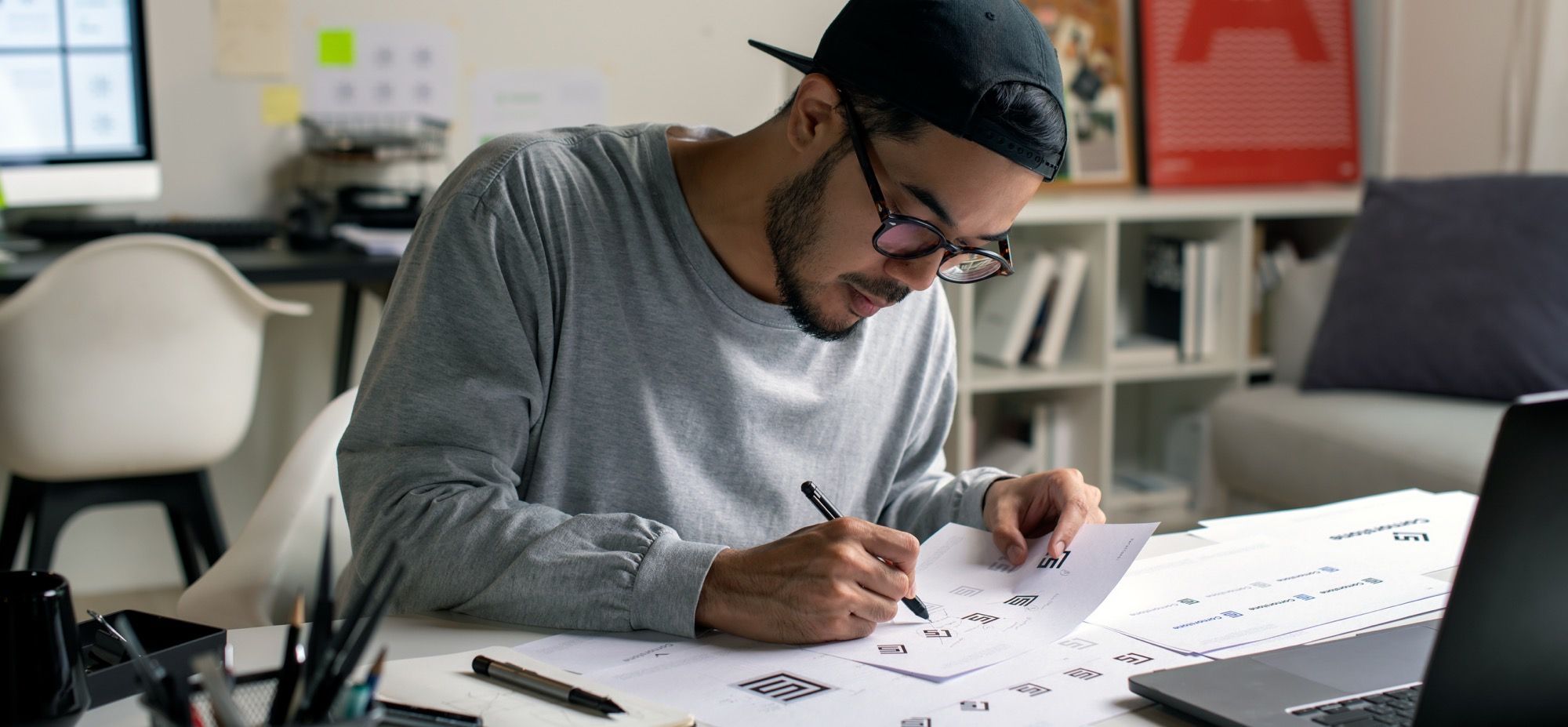Designer arbeider med wireframes og skisser på papir for å utvikle en helhetlig grafisk profil