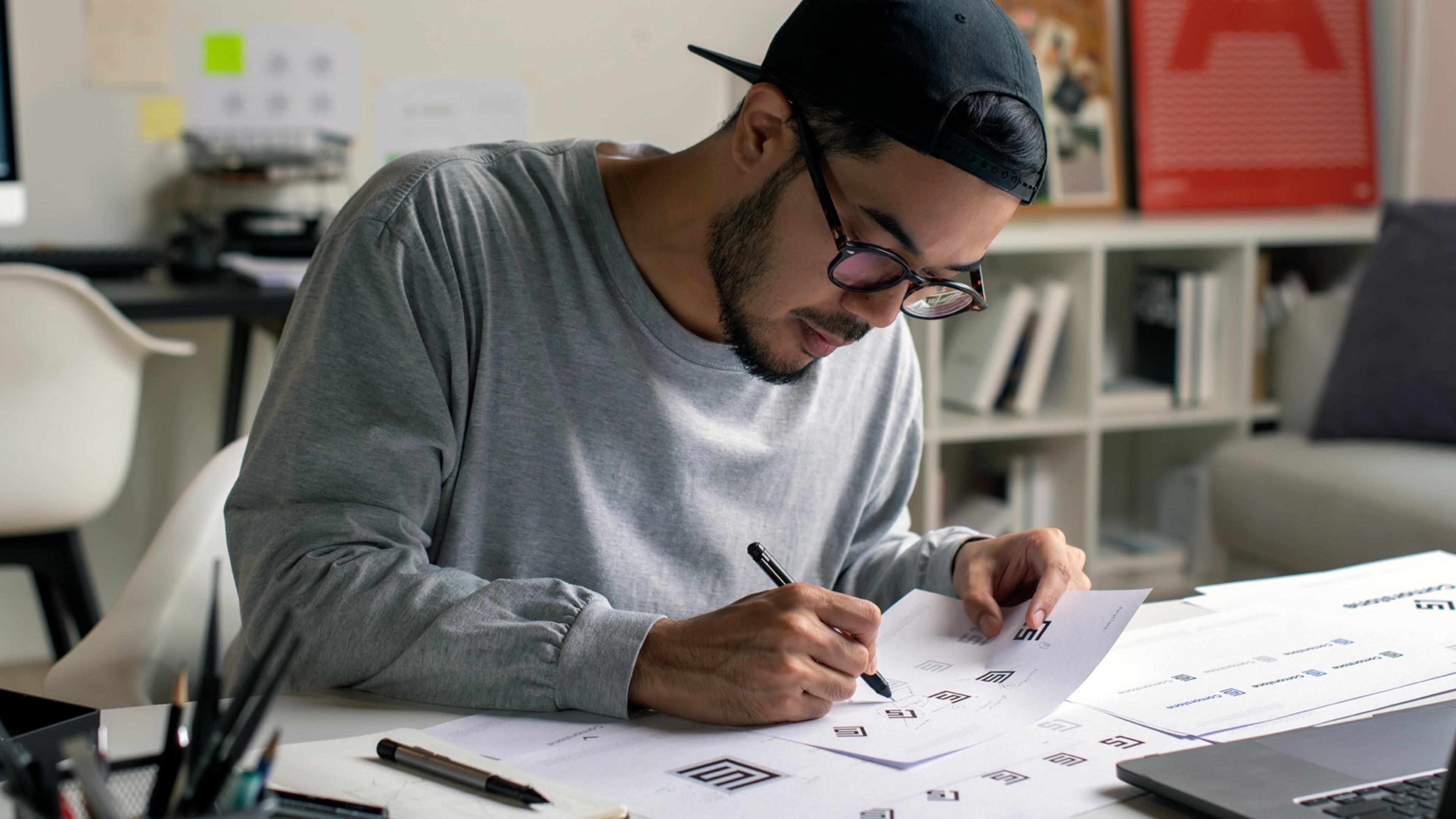 Designer arbeider med wireframes og skisser på papir for å utvikle en helhetlig grafisk profil