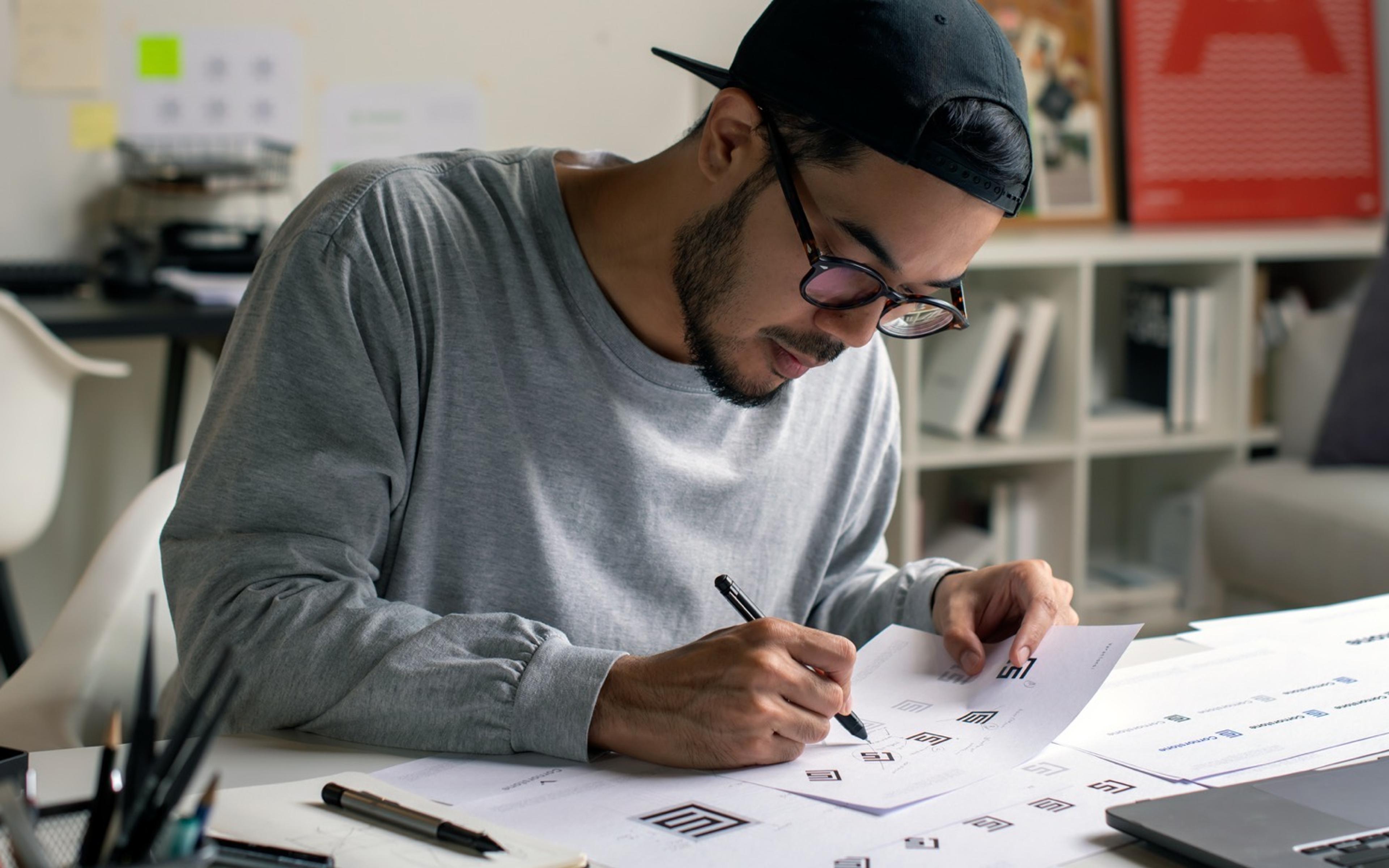 Designer arbeider med wireframes og skisser på papir for å utvikle en helhetlig grafisk profil