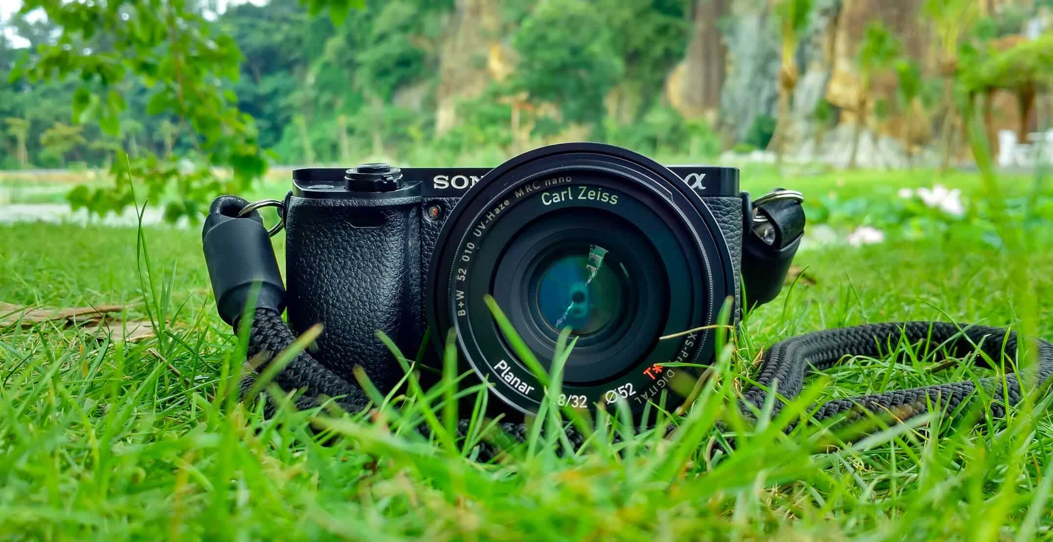 Sony Alpha kamera med Carl Zeiss optikk liggende på grønt gress, illustrerer profesjonell videoutstyr for merkevarebygging