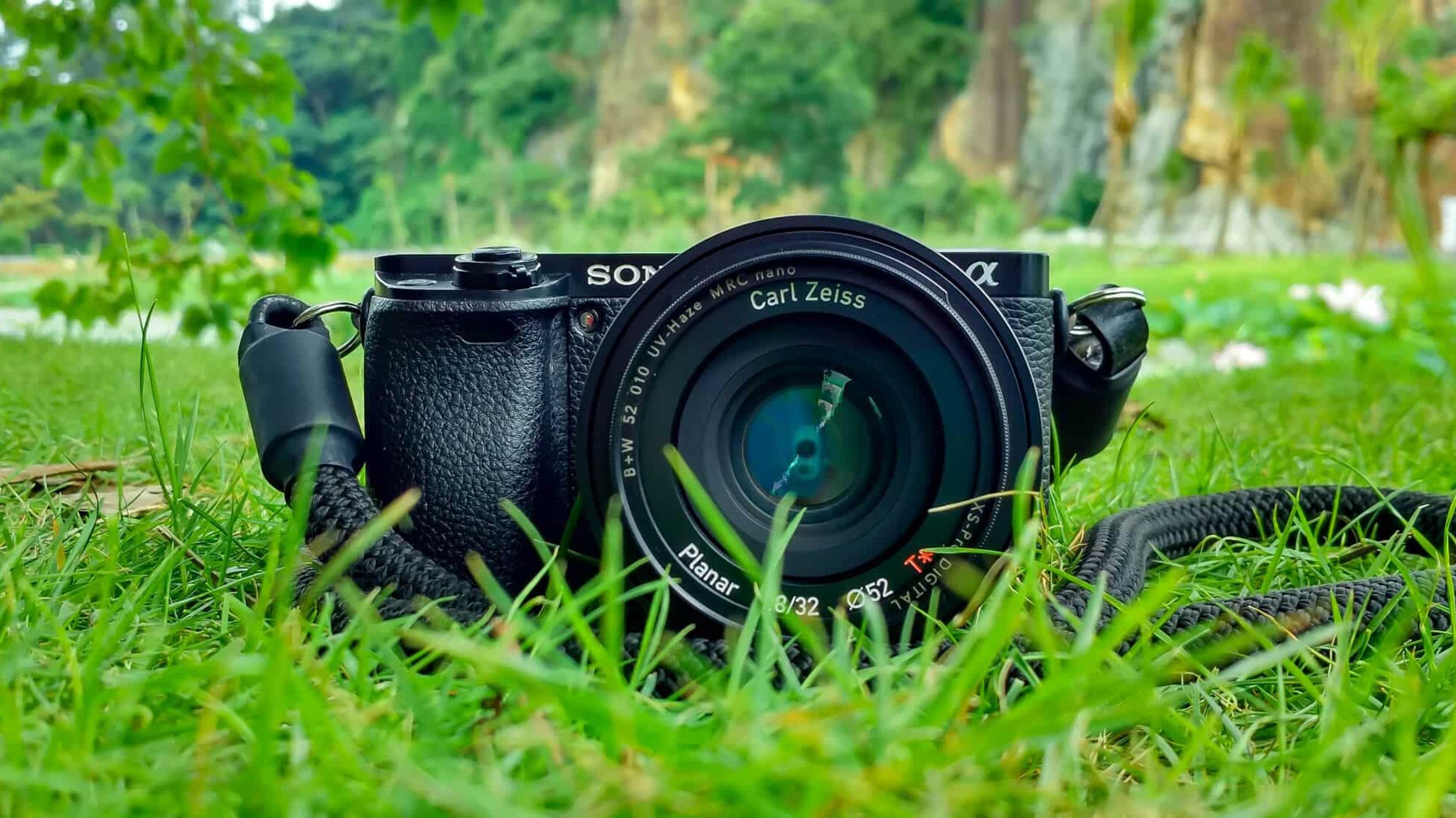Sony Alpha kamera med Carl Zeiss optikk liggende på grønt gress, illustrerer profesjonell videoutstyr for merkevarebygging