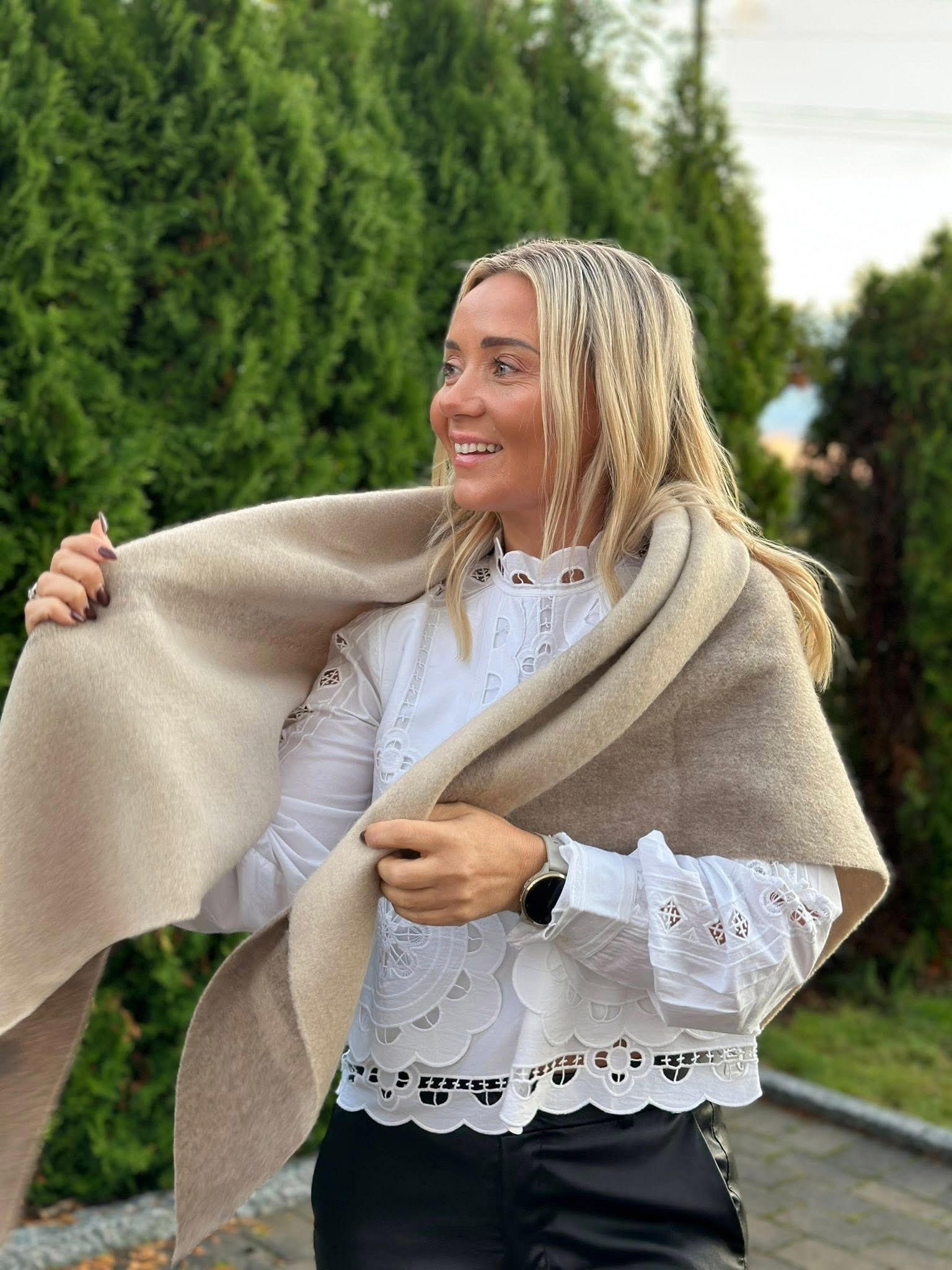 Portrett av Cecilie Eriksen hos Klara Tønsberg som står foran en grønn hekk og viser frem årets kolleksjon