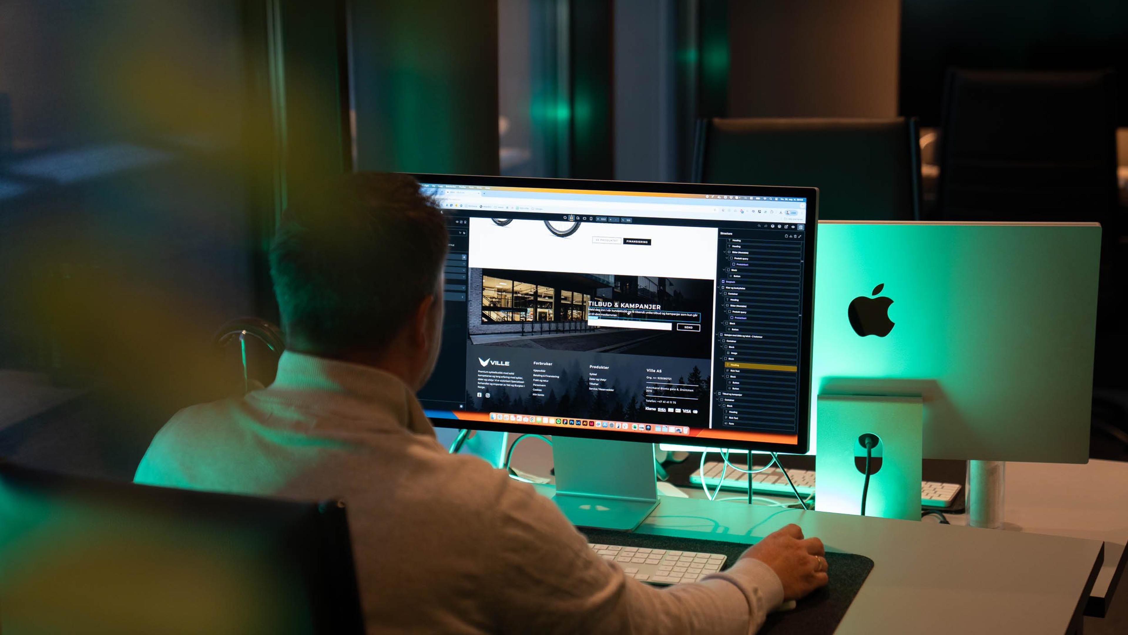 Webutvikler jobber med Sanity CMS og nettside på stor skjerm på kontor