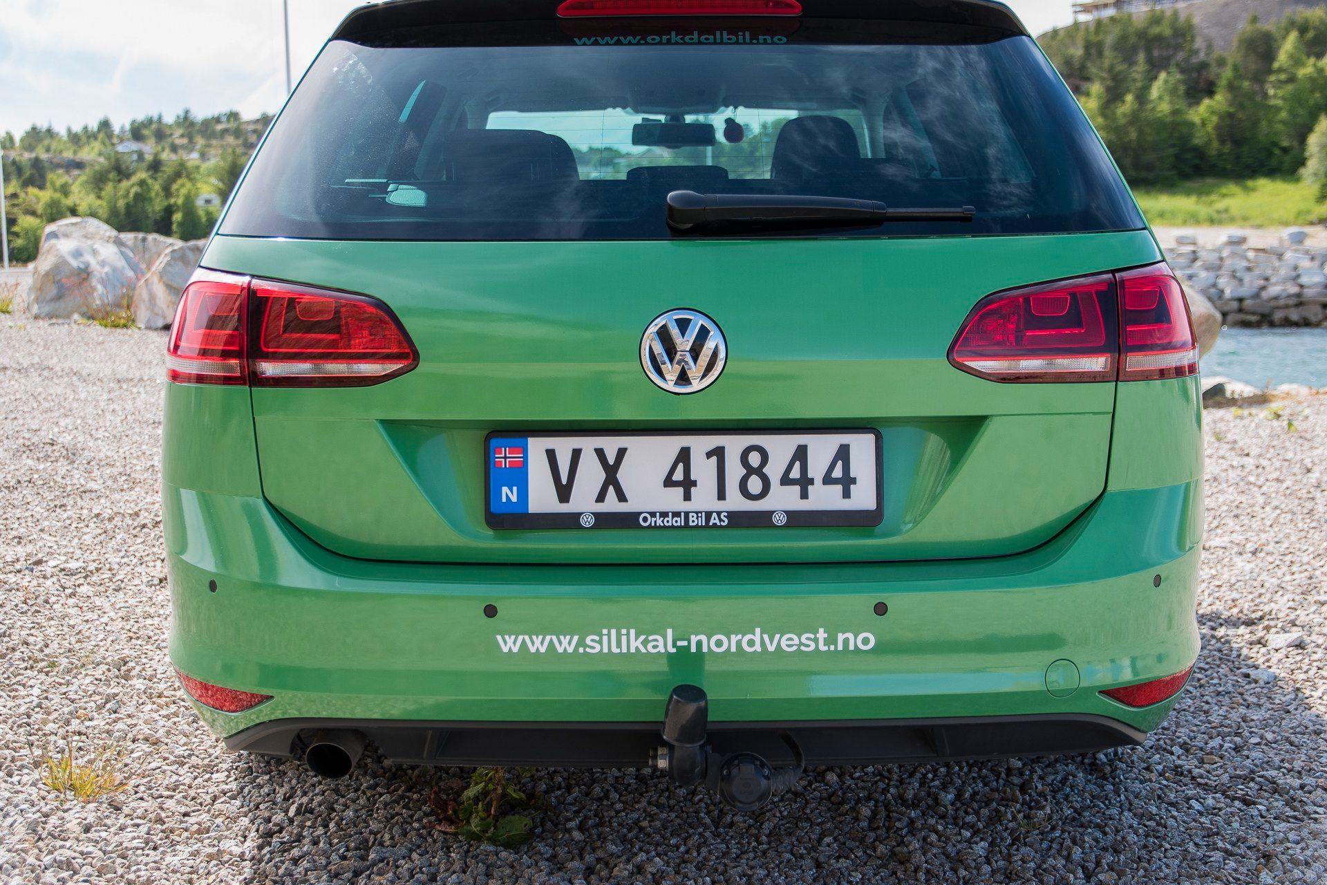 Grønn Volkswagen stasjonsvogn med nummerskilt VX 41844 og www.silikal-nordvest.no på bakre skjerm, parkert på grusområde.