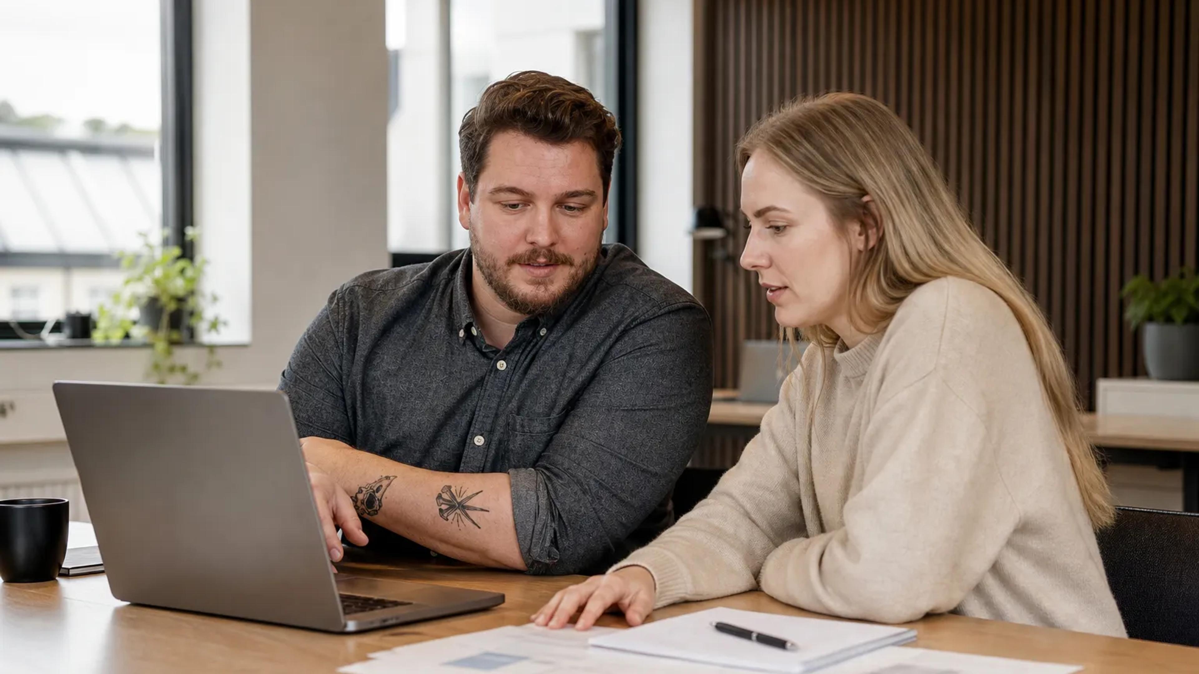 En bedriftseier og en markedsfører planlegger søkeord og budsjett ved et bord.