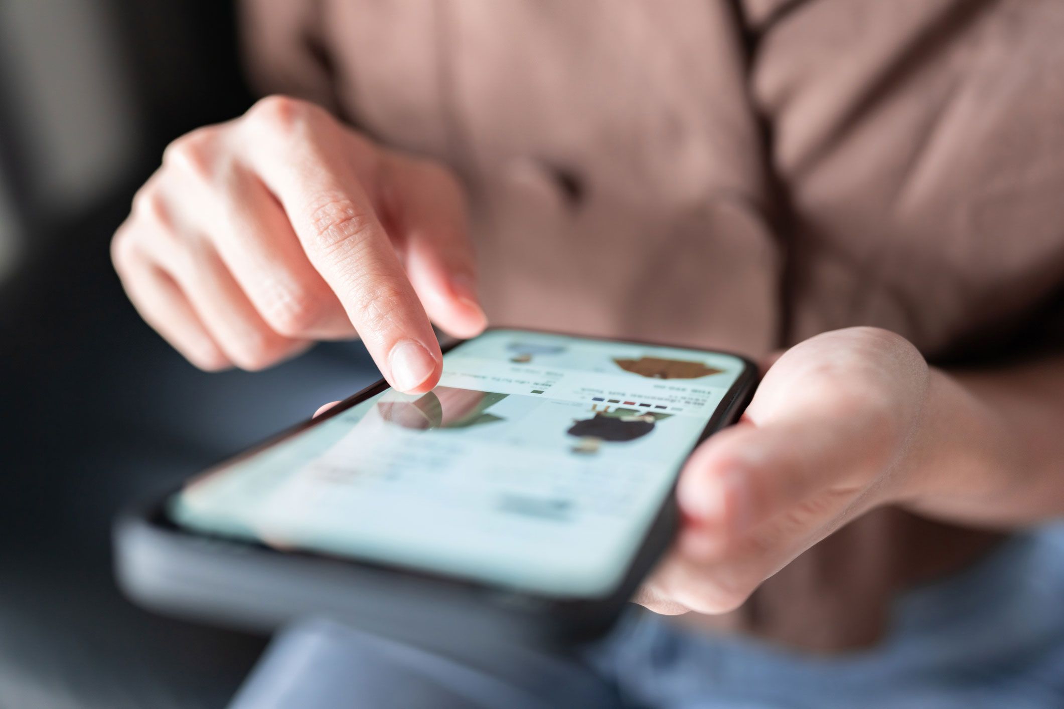 En person som sitter og ser igjennom en nettbutikk i Shopify på mobilen