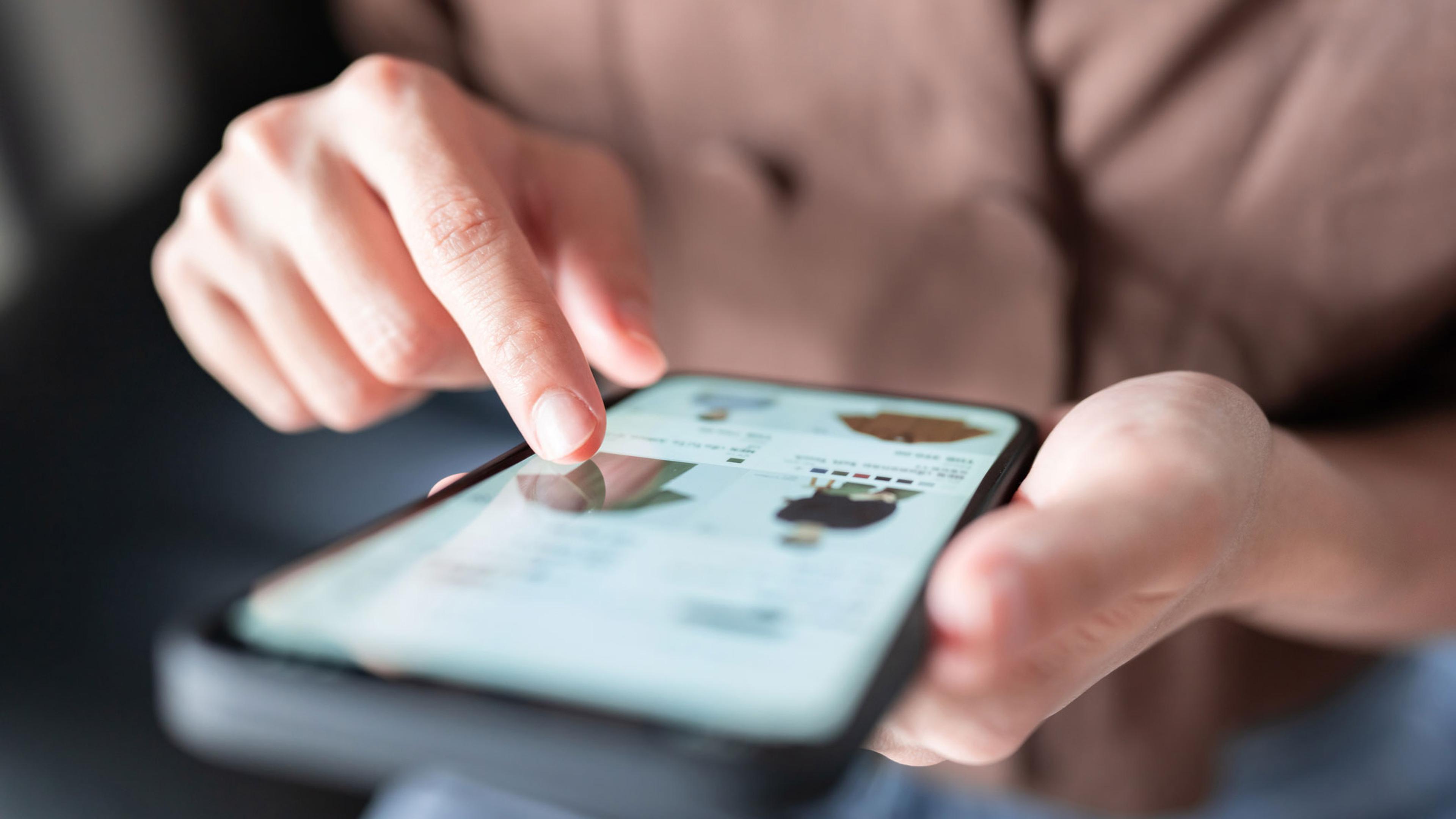En person som sitter og ser igjennom en nettbutikk i Shopify på mobilen
