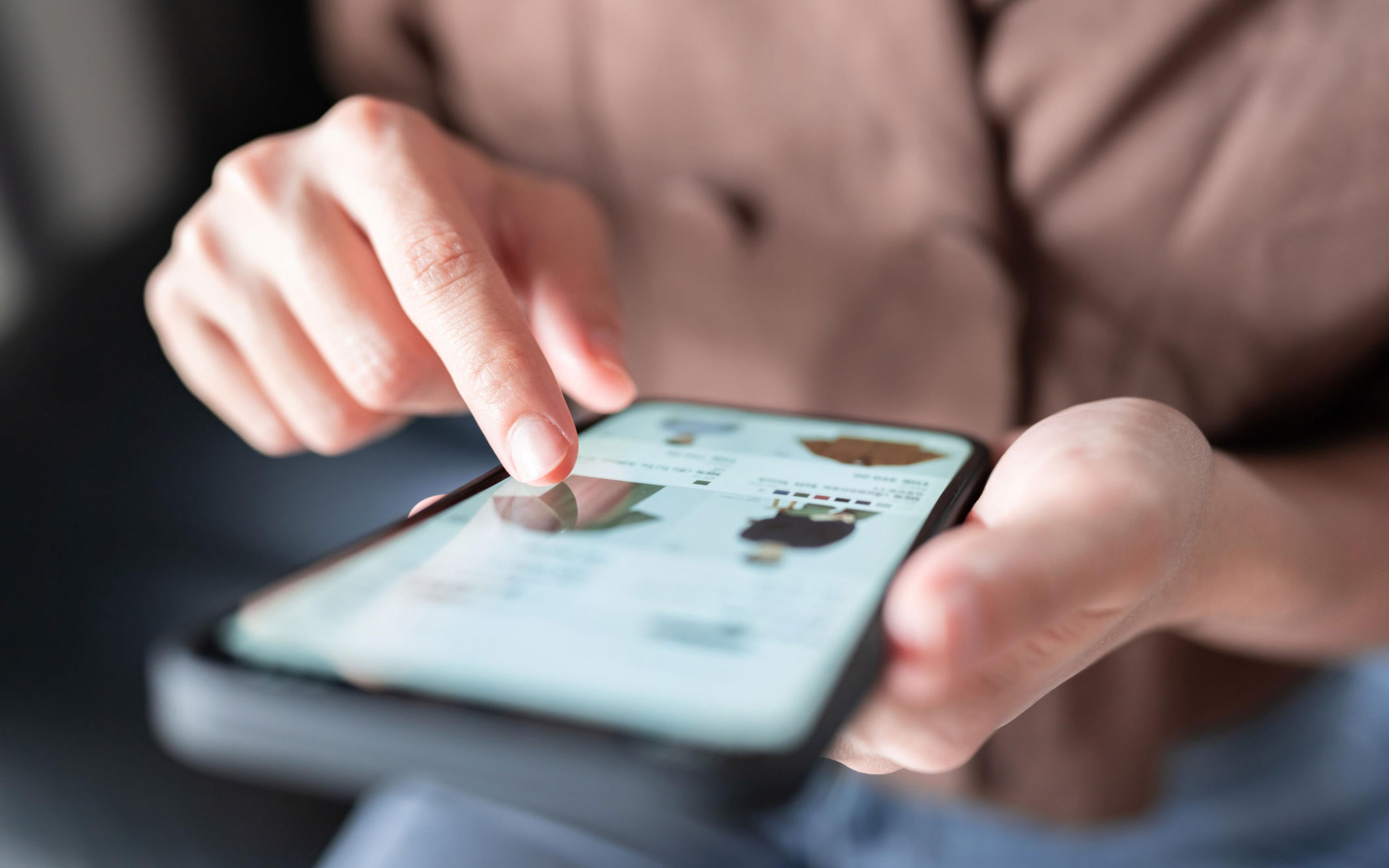 En person som sitter og ser igjennom en nettbutikk i Shopify på mobilen