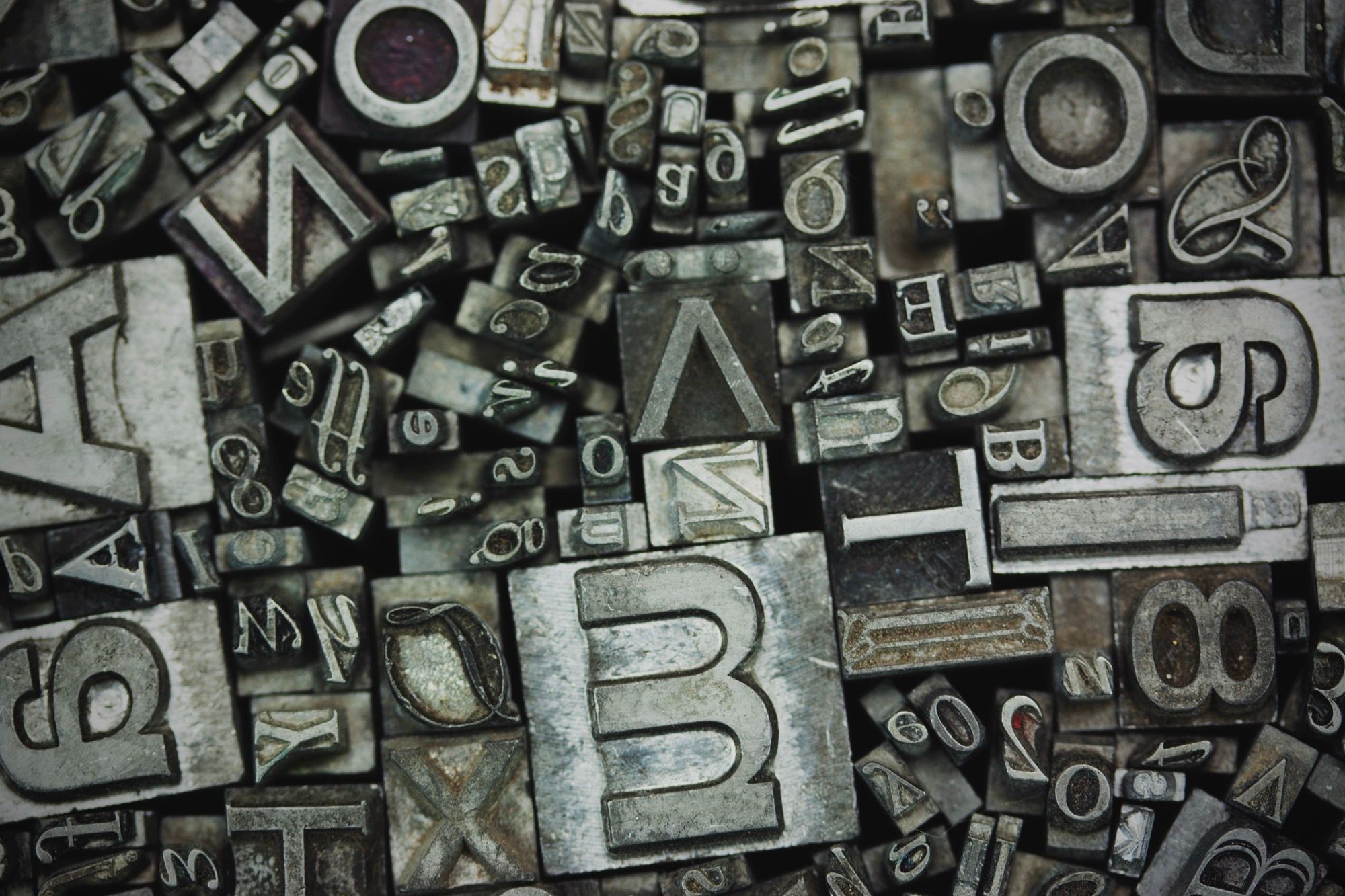 Metall typografibokstaver og tall ordnet som dekorasjon, illustrerer designelementer som logoer og typografi