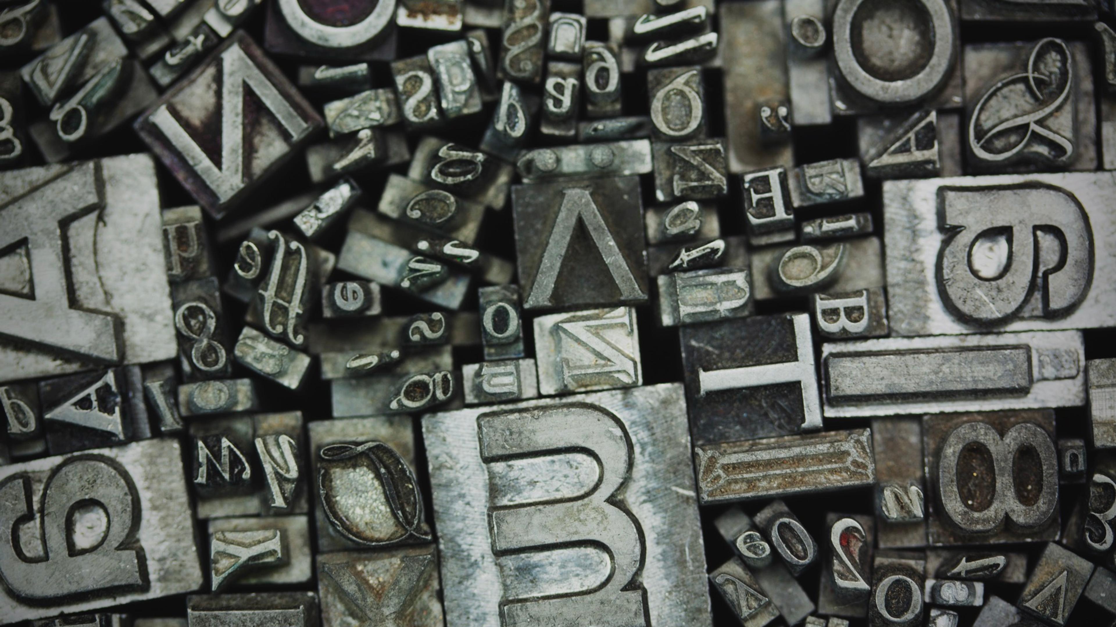 Metall typografibokstaver og tall ordnet som dekorasjon, illustrerer designelementer som logoer og typografi