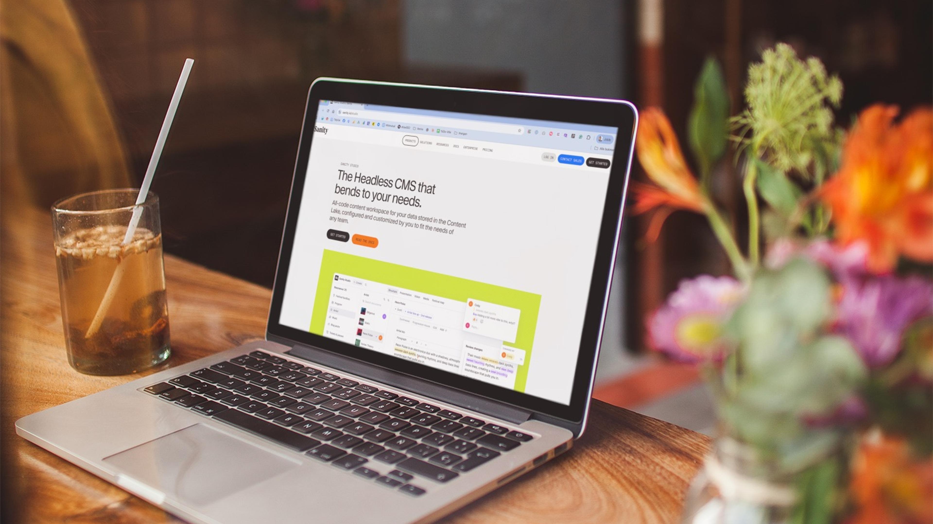 Laptop som viser Sanity headless CMS-grensesnittet, omgitt av grønn natur — symboliserer moderne, fleksibel innholdshåndtering
