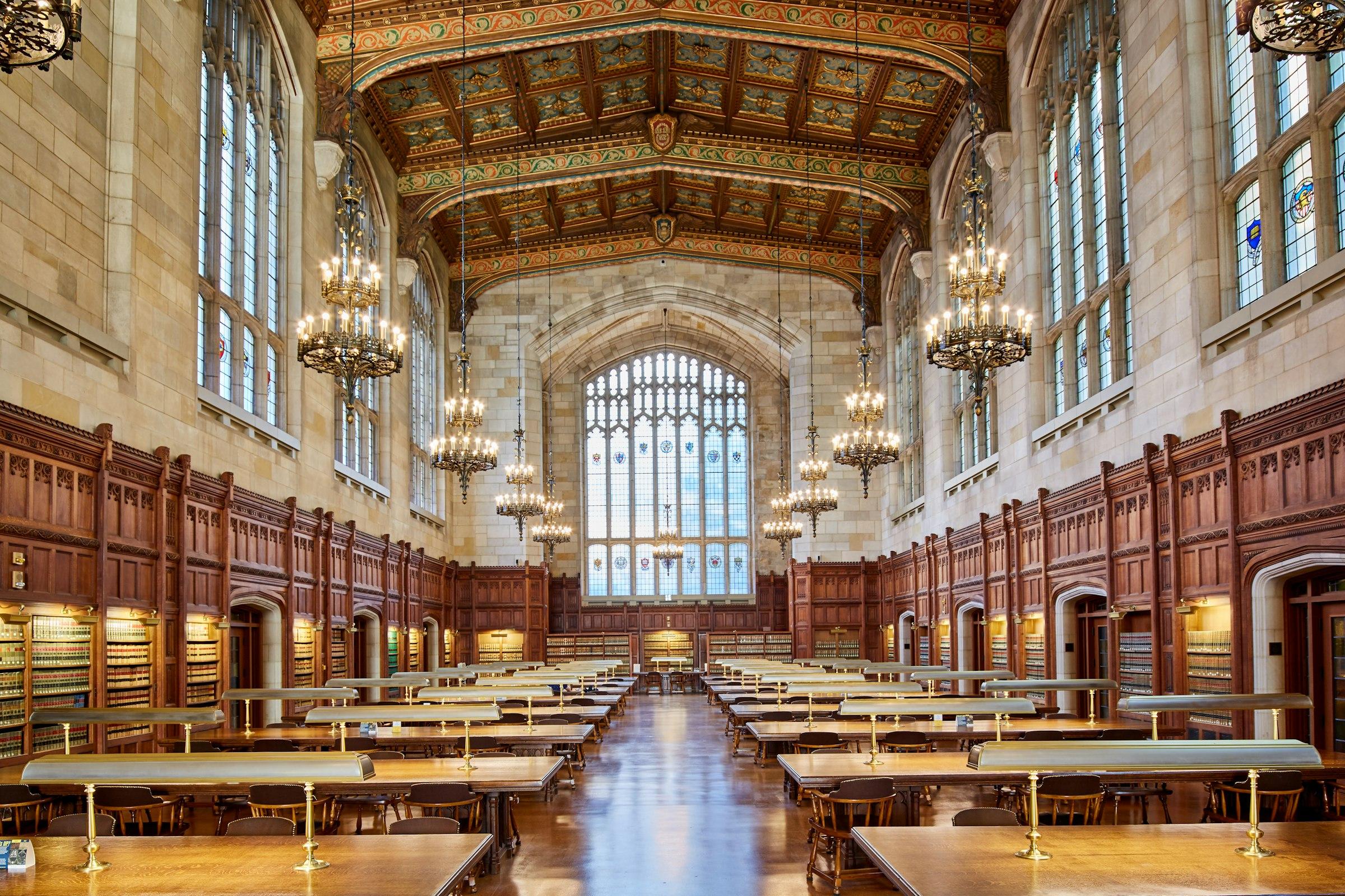 A reading room with chandeliers above rows of desks