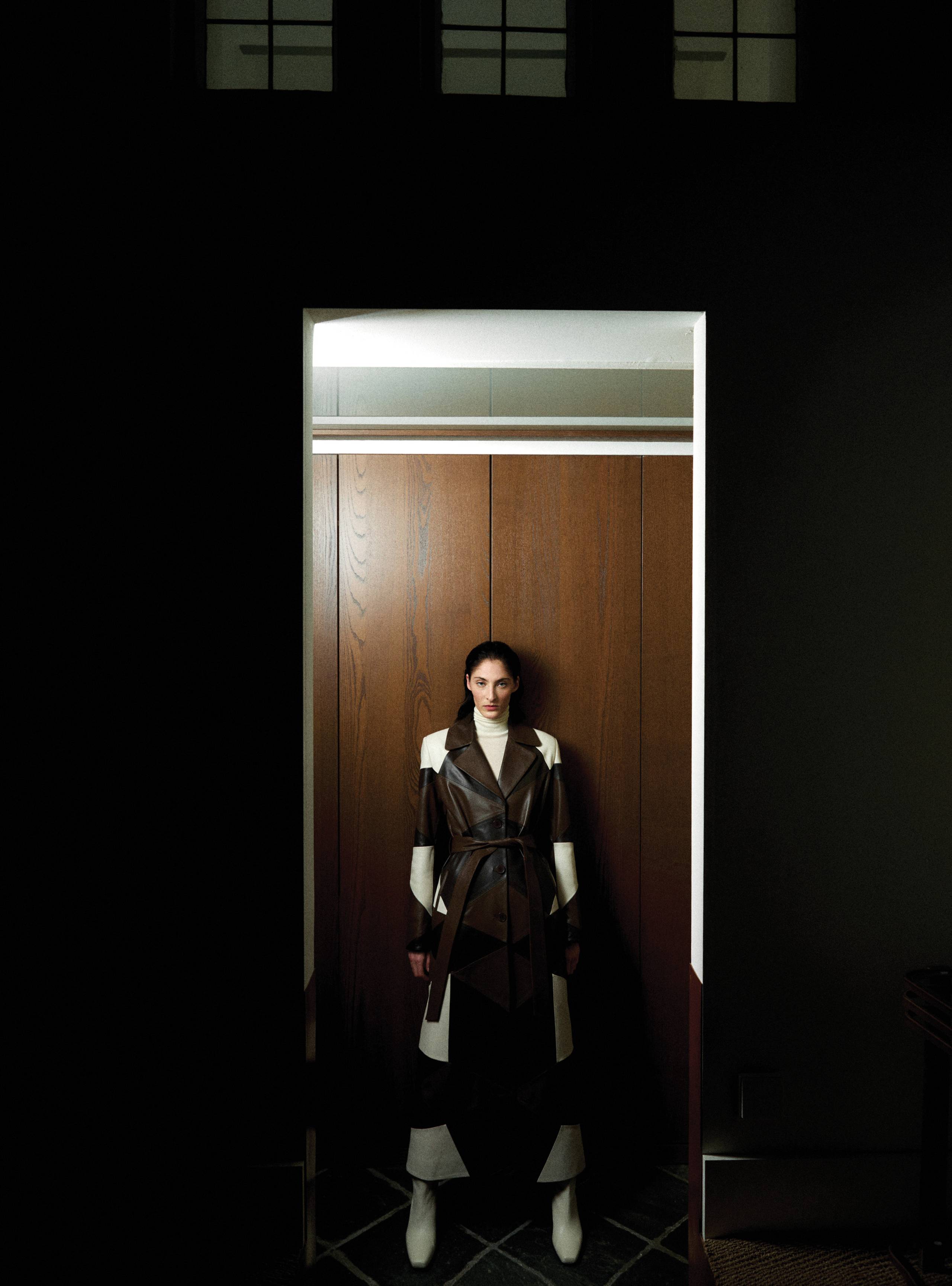A model standing in a doorway wearing the Sonja Cocoa Vanilla Marron coat