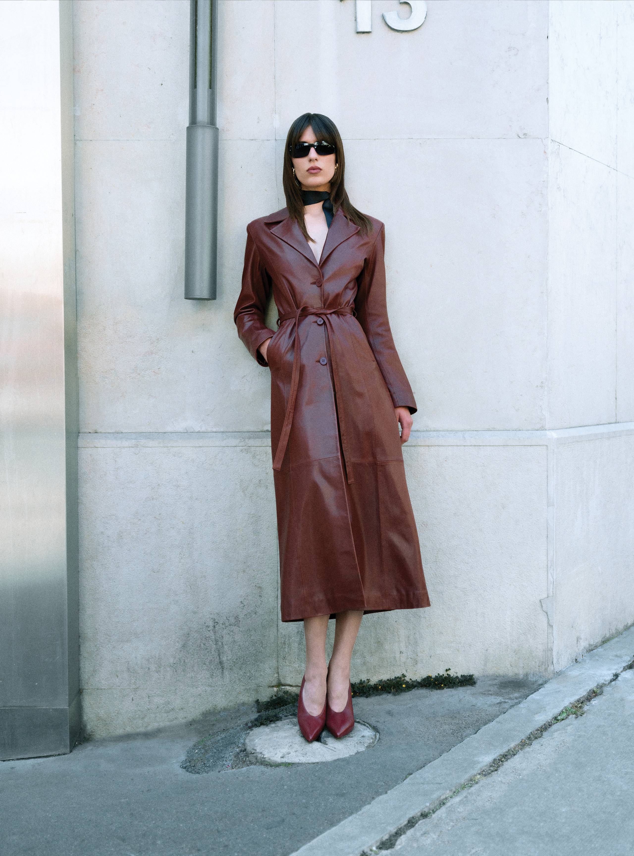 A model standing straight wearing the Tamara Dark Cherry long leather coat