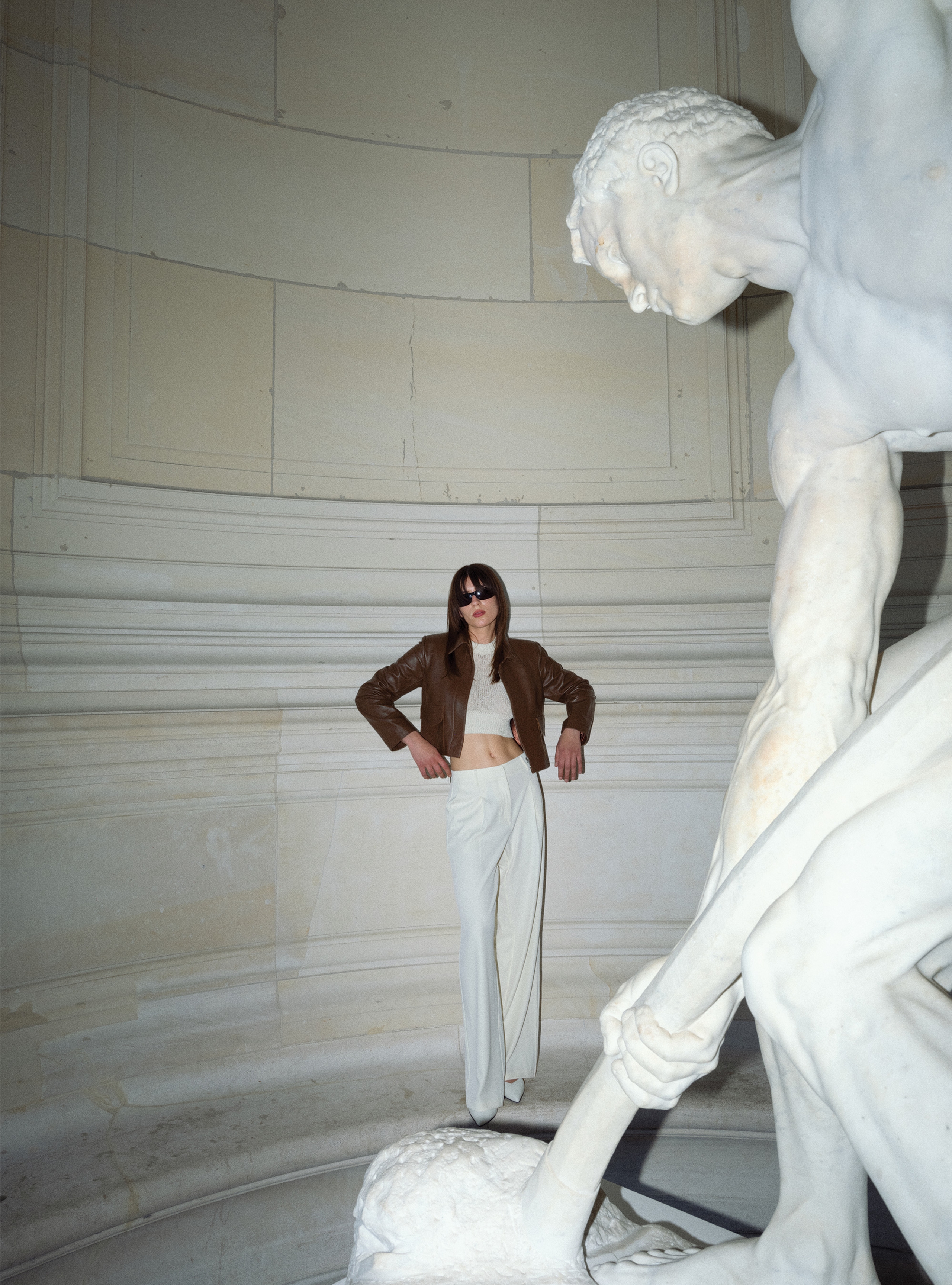 A model standing in front of a statue wearing the Bleeker Milk Chocolate jacket