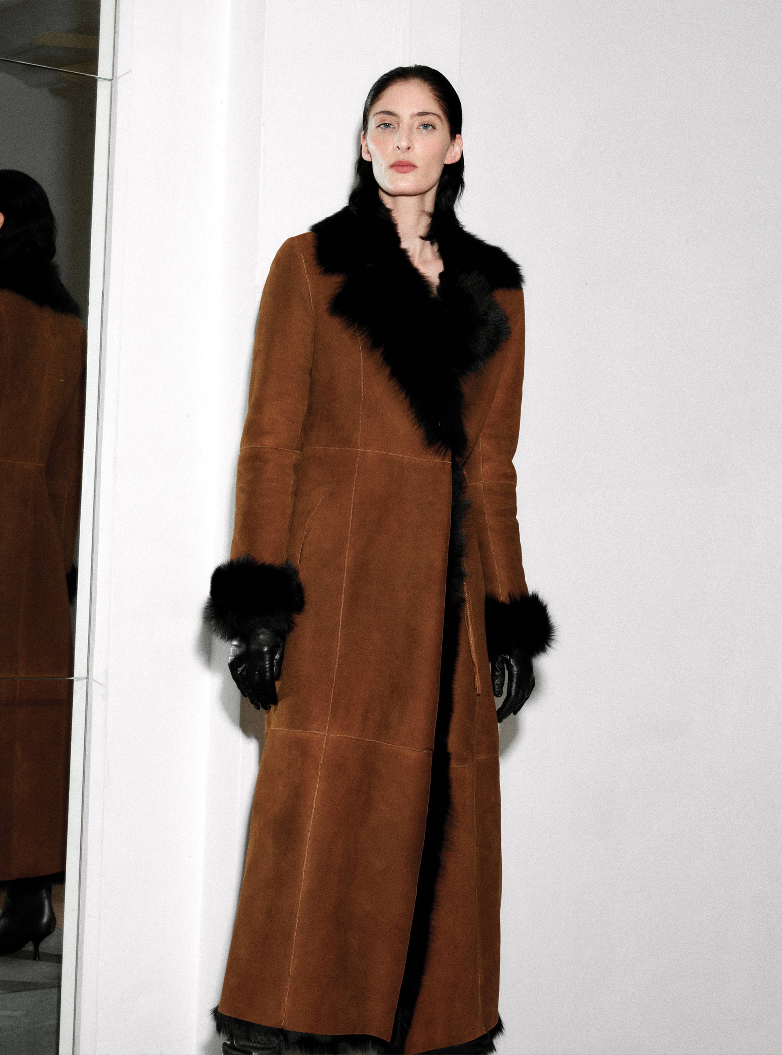 A model standing straight wearing the Joni Cognac Black long shearling coat