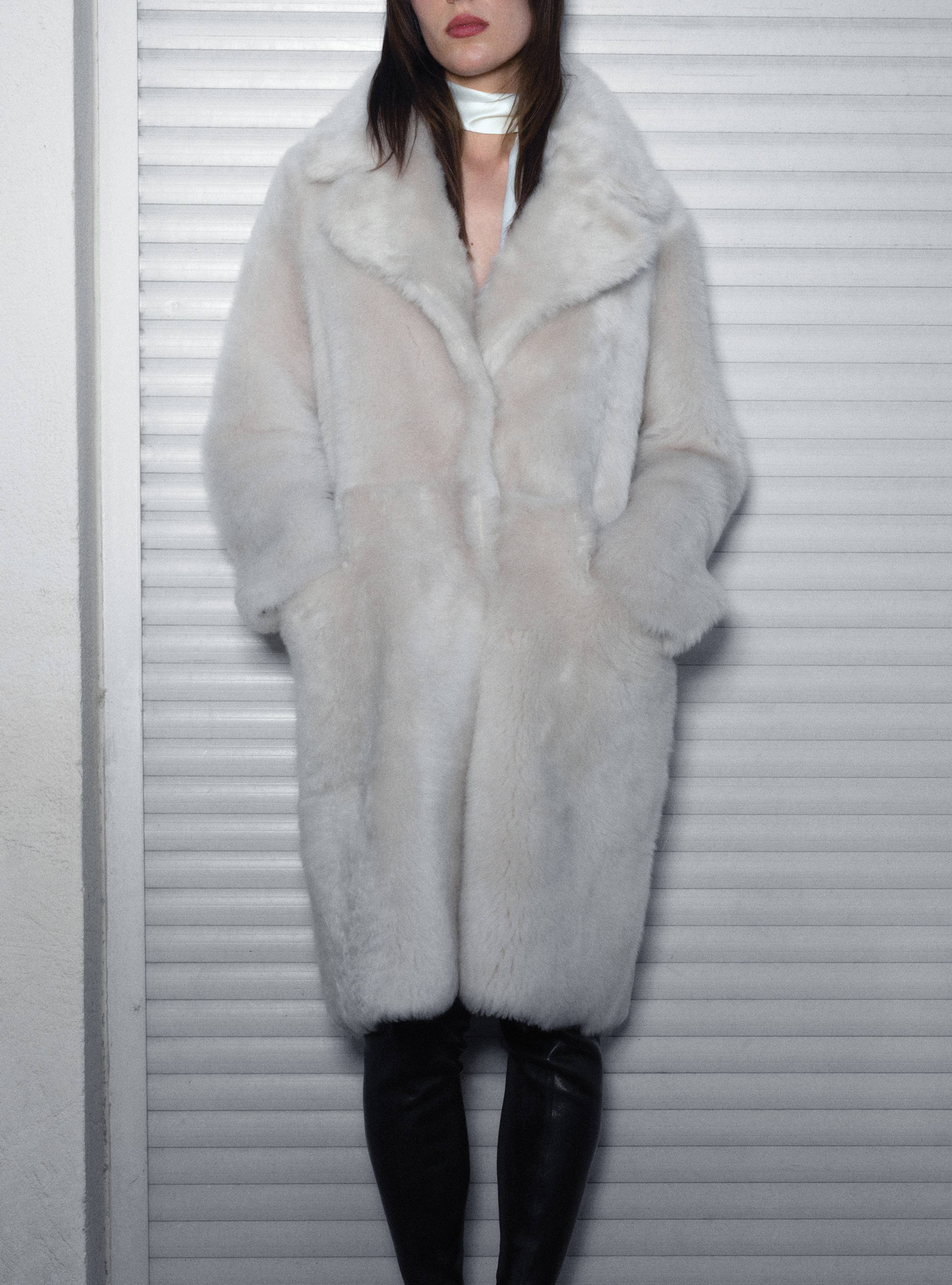 A model standing wearing the Evit Ivory apres ski shearling coat