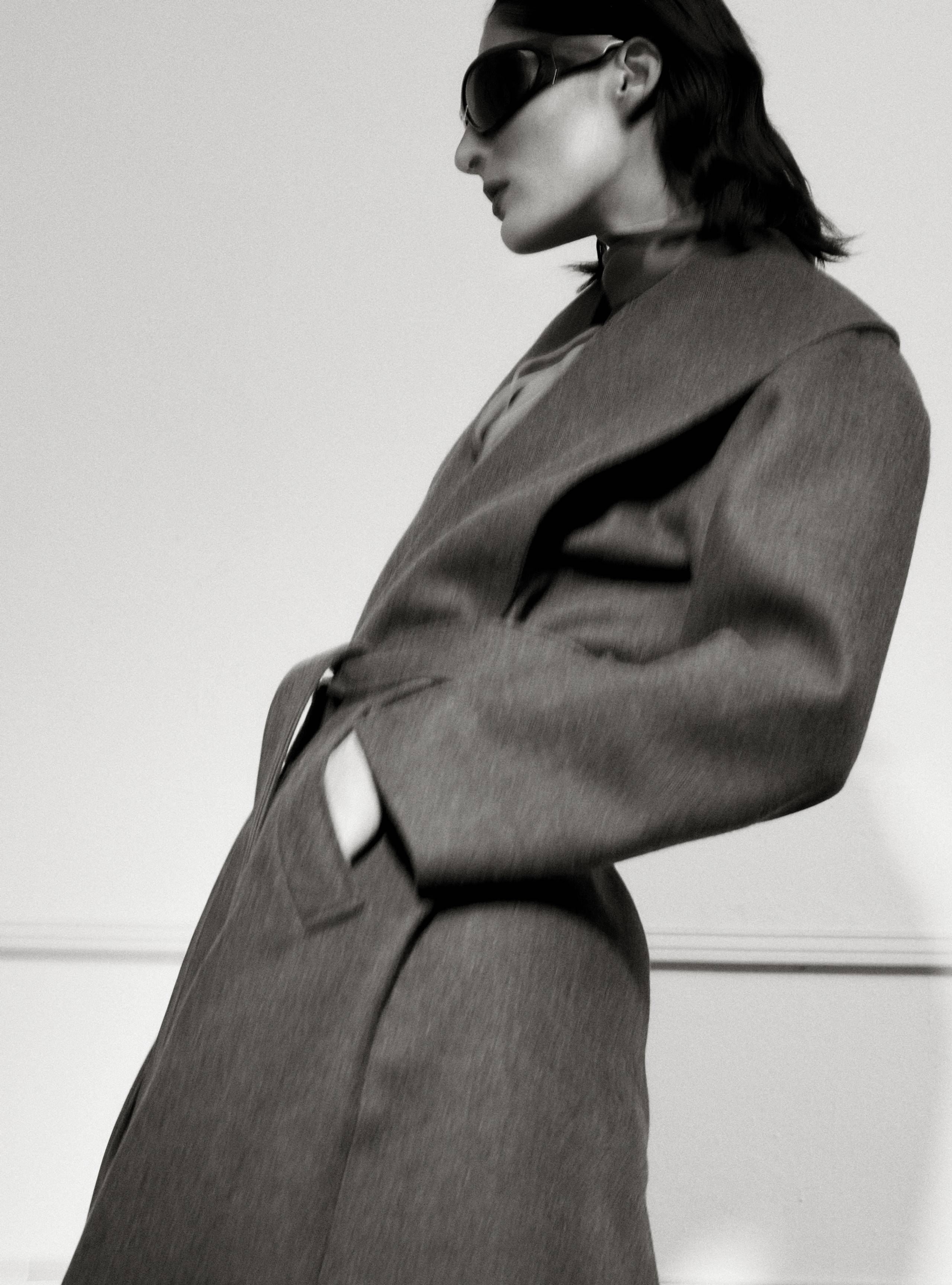 A model standing sideways wearing the Lucee Thunder long blanket coat
