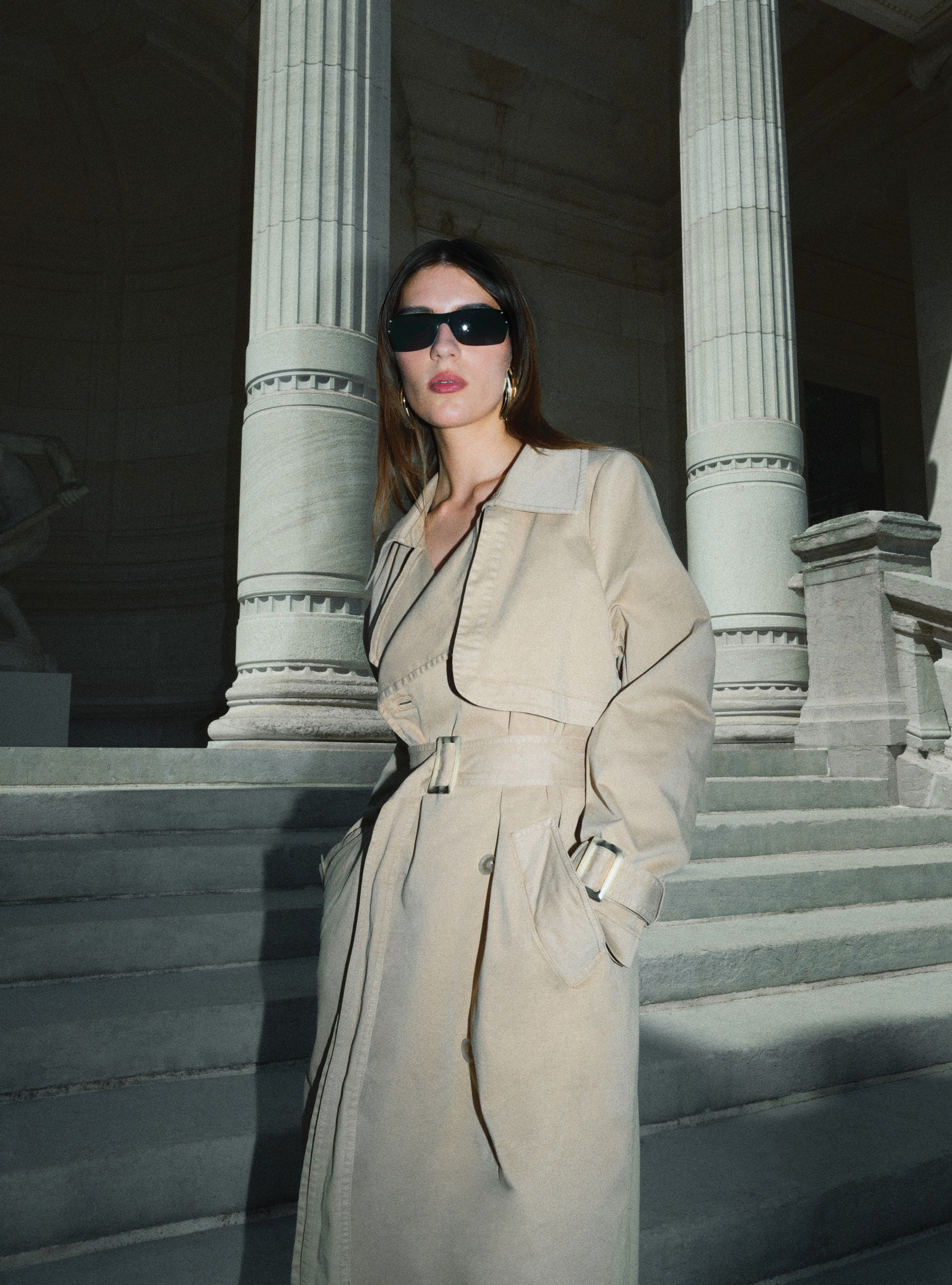 A model standing sideways wearing the Harriet Canvas Khaki trench coat