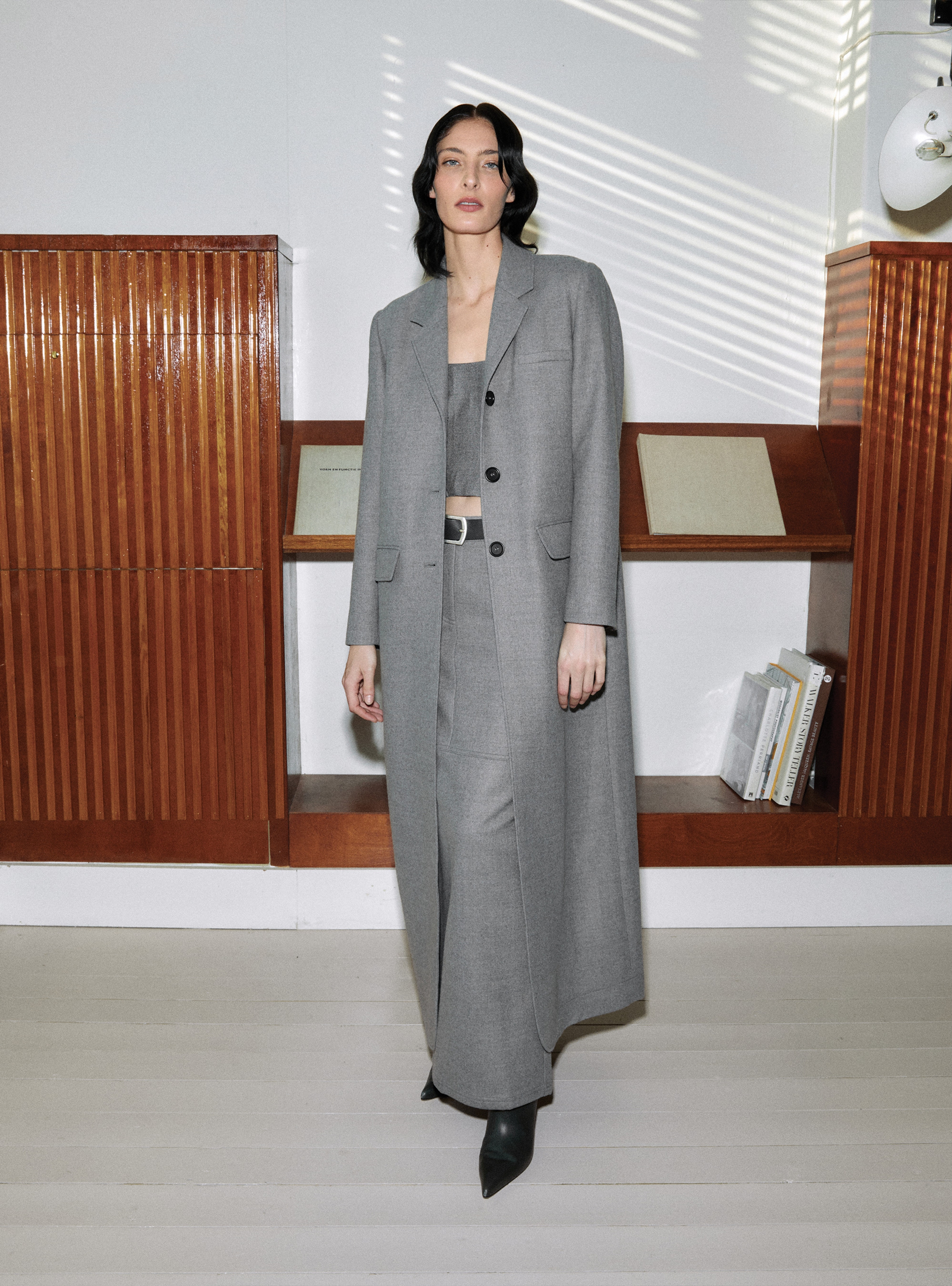 A model standing straight wearing the Celine Light Grey long suit coat