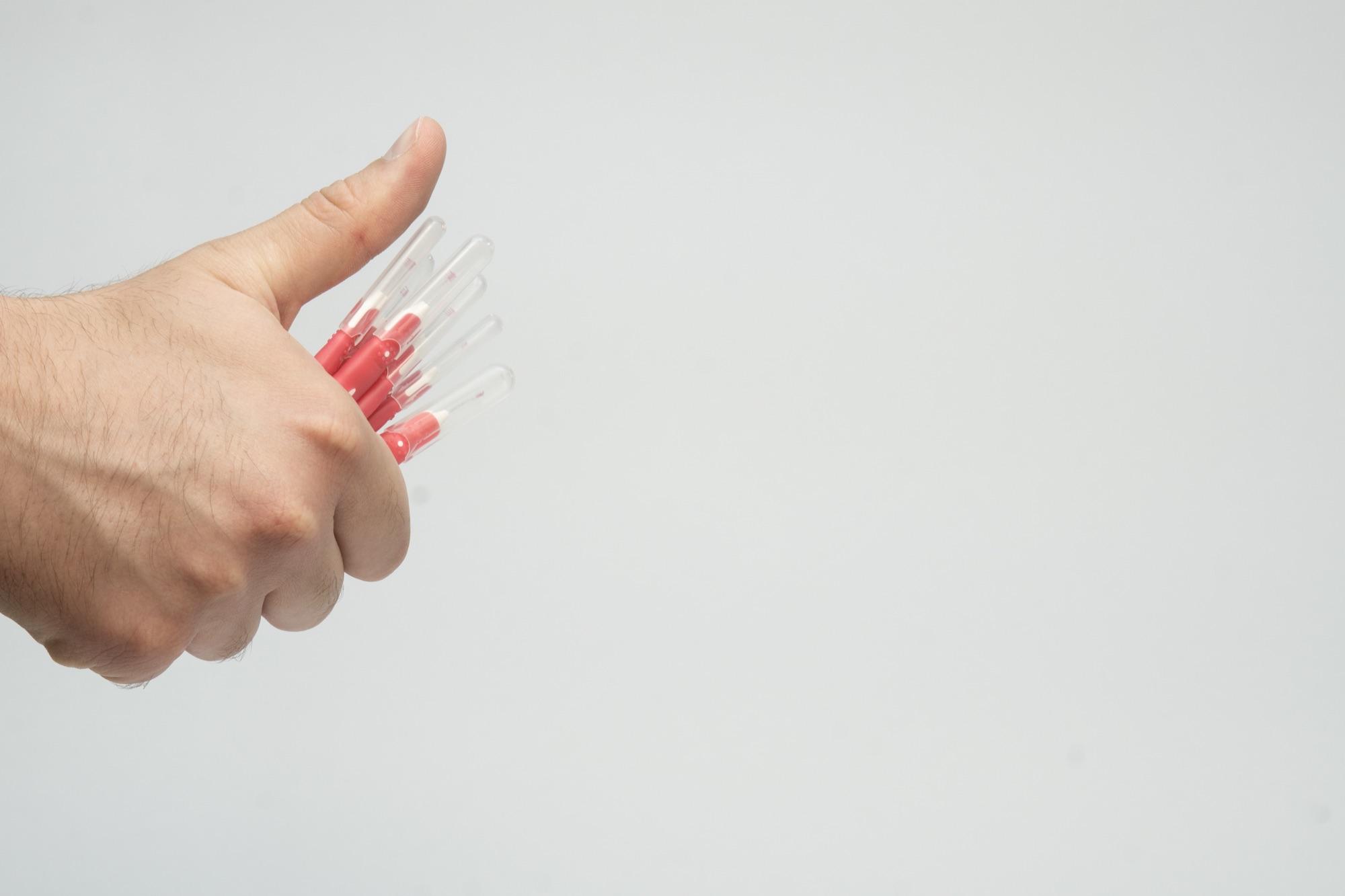 Hånd som holder fram flere mellomromsbørster mot nøytral bakgrunn